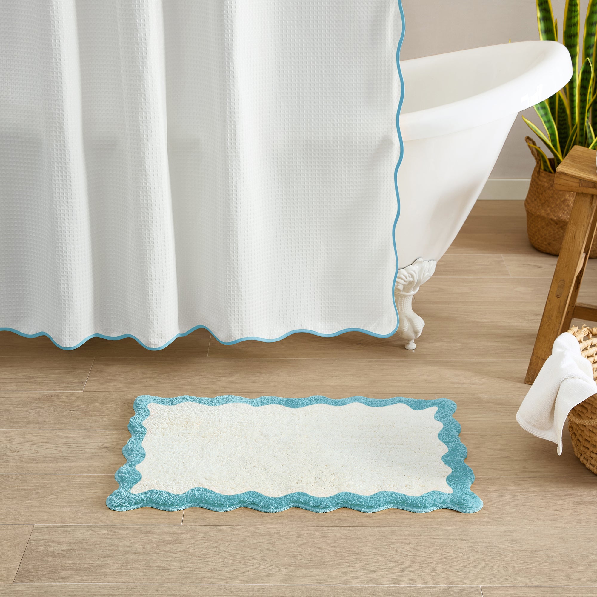 Bathroom with a white bathtub, shower curtain, and bath mat on a wooden floor.