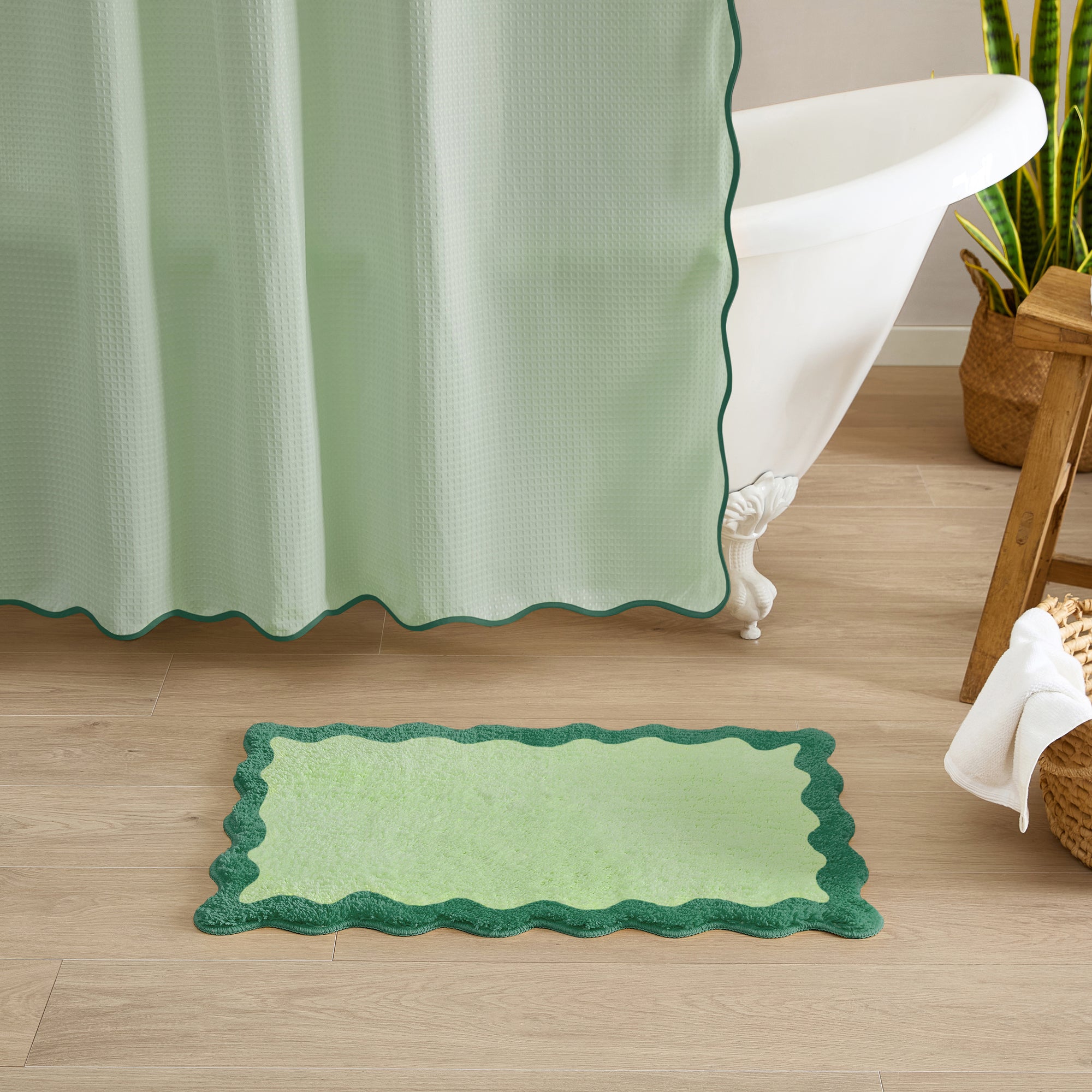 Green bath mat on a wooden floor with a shower curtain in the background