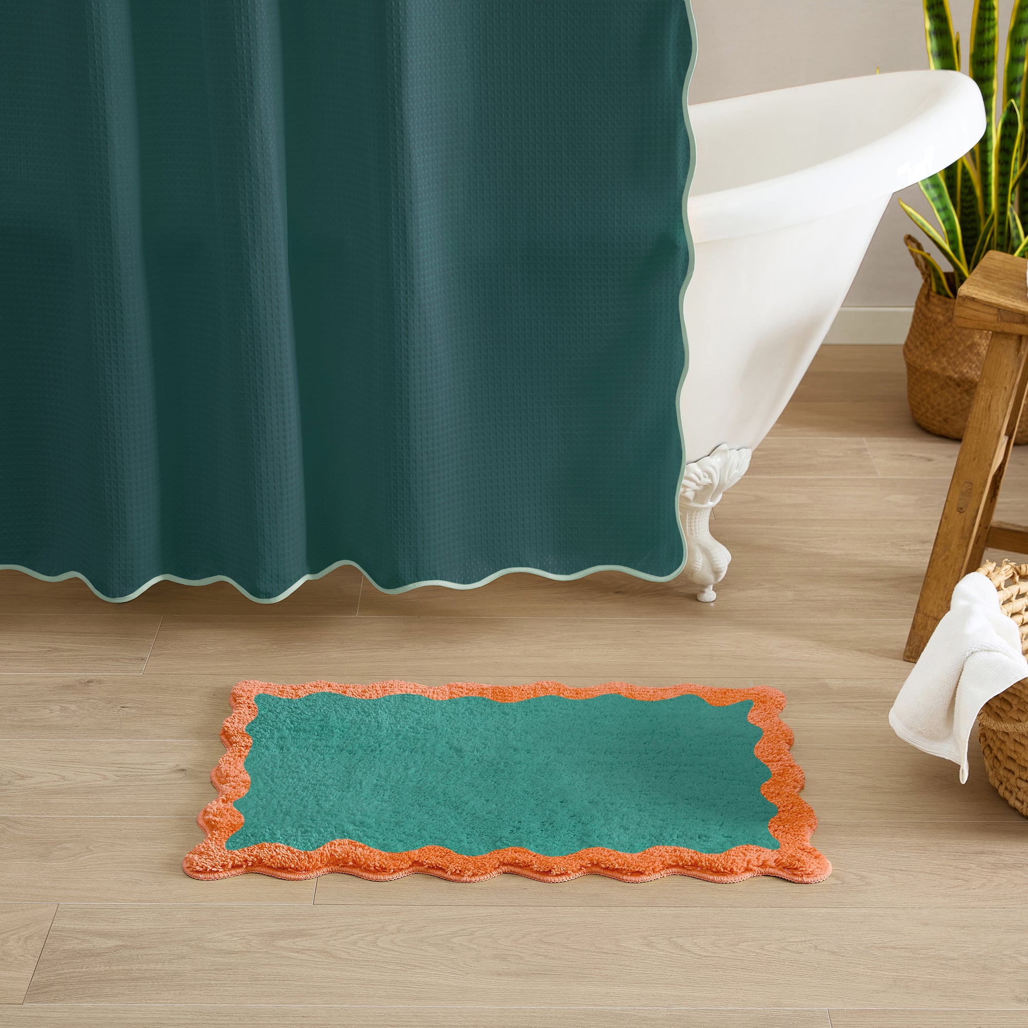 Teal bath mat with orange border on wooden floor next to bathtub
