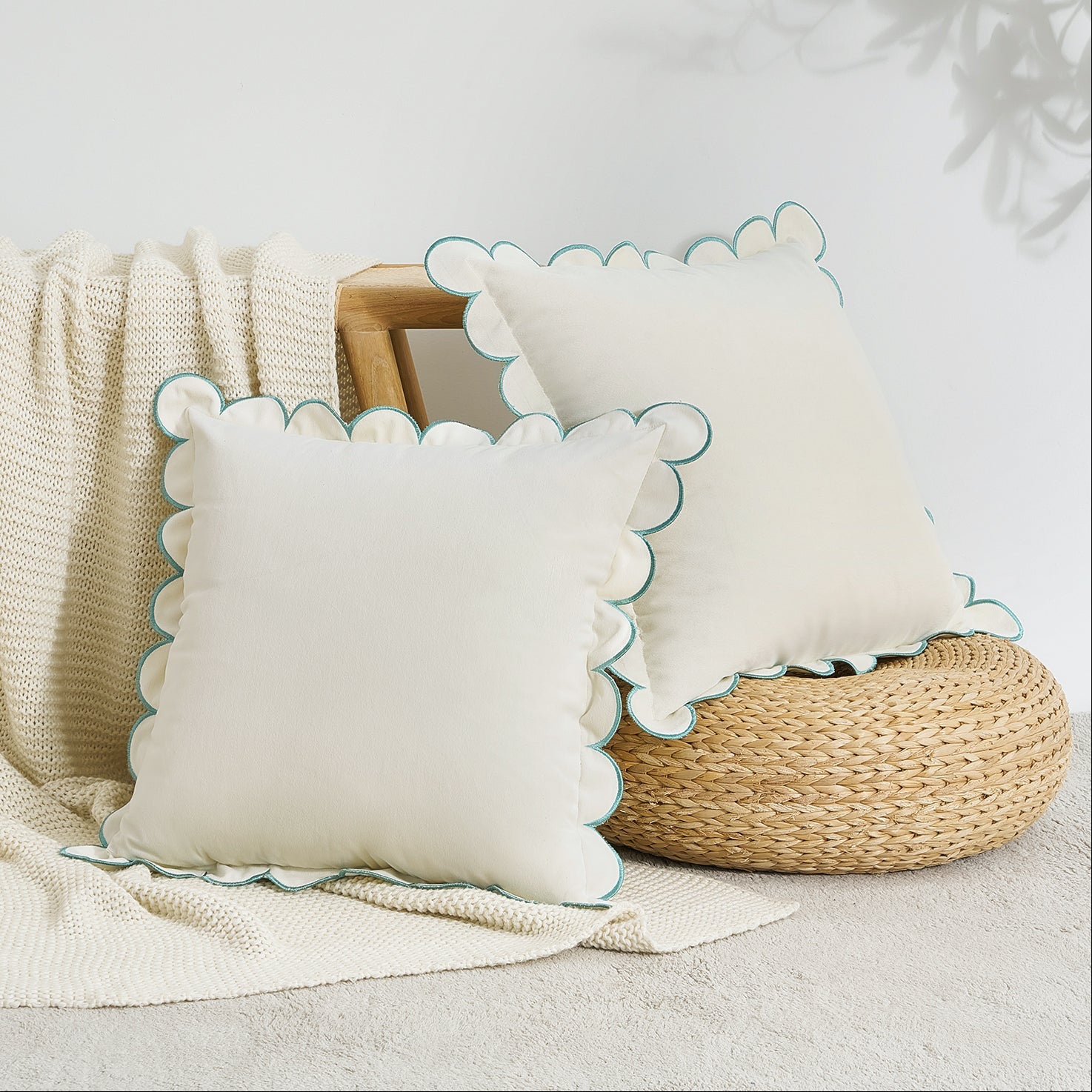 Two decorative pillows with scalloped edges on a textured surface.