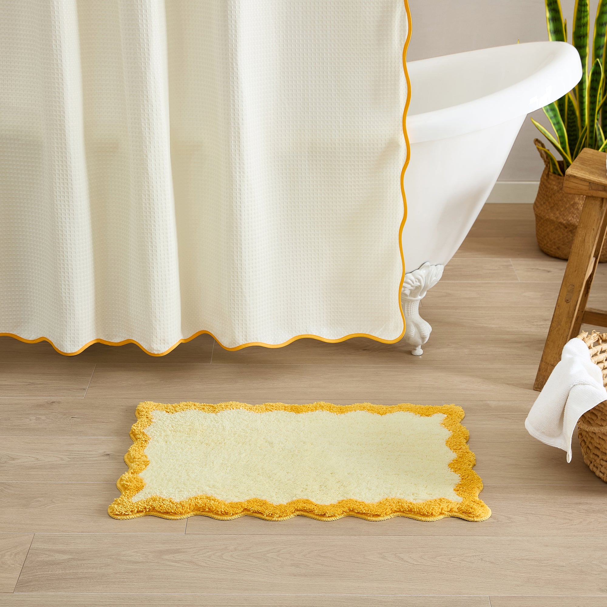 Bath mat with yellow border in front of a bathtub