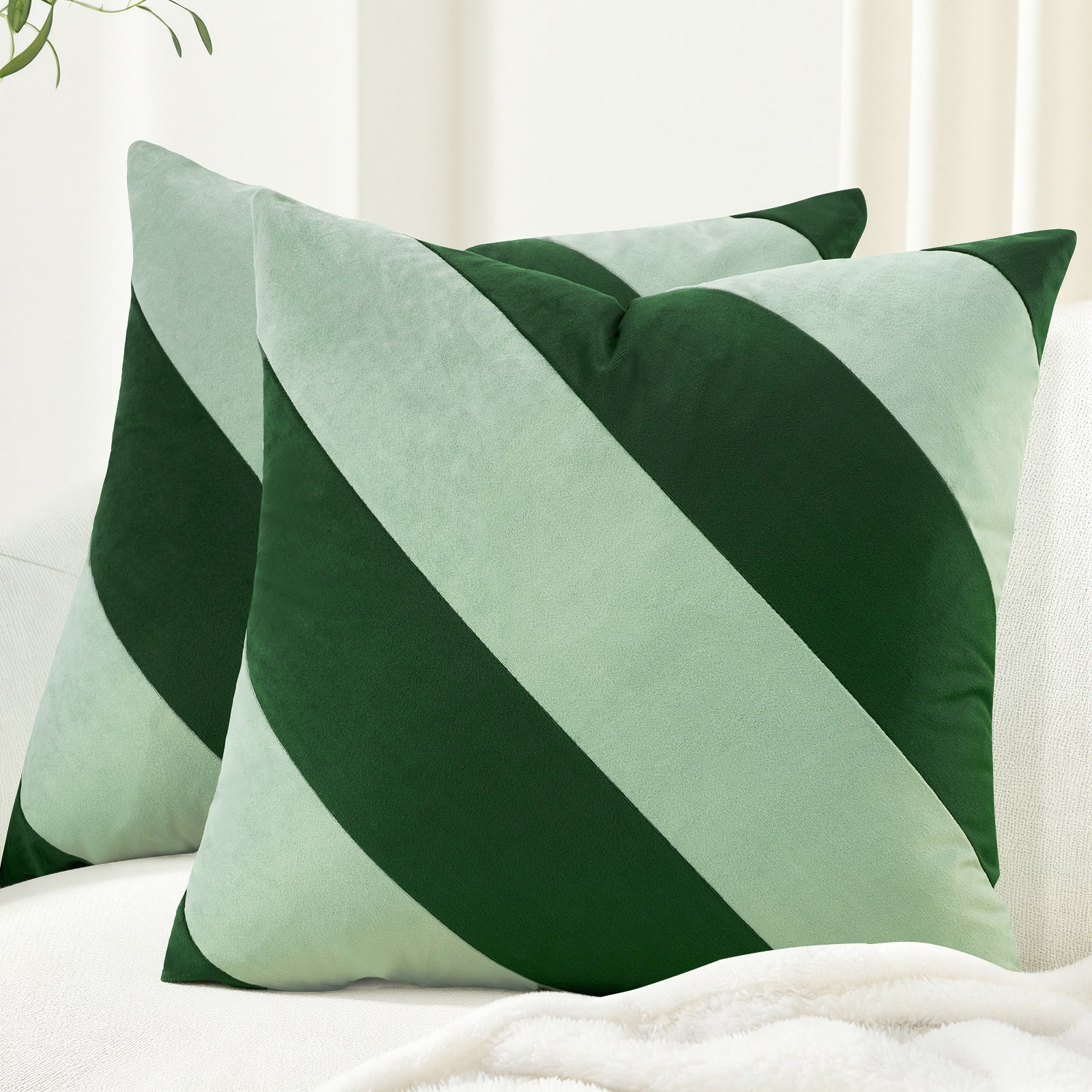 Two green and white striped pillows on a white surface.