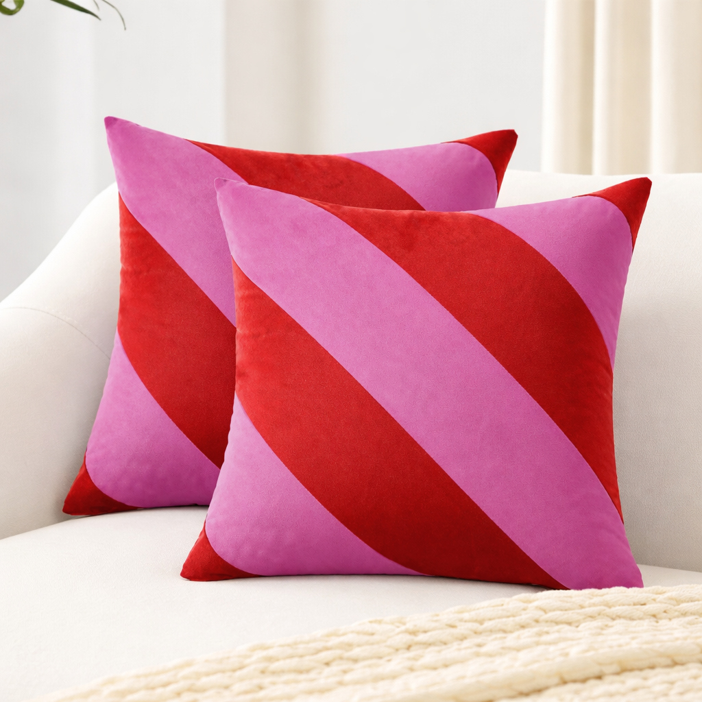 Two pink and red striped pillows on a white couch.