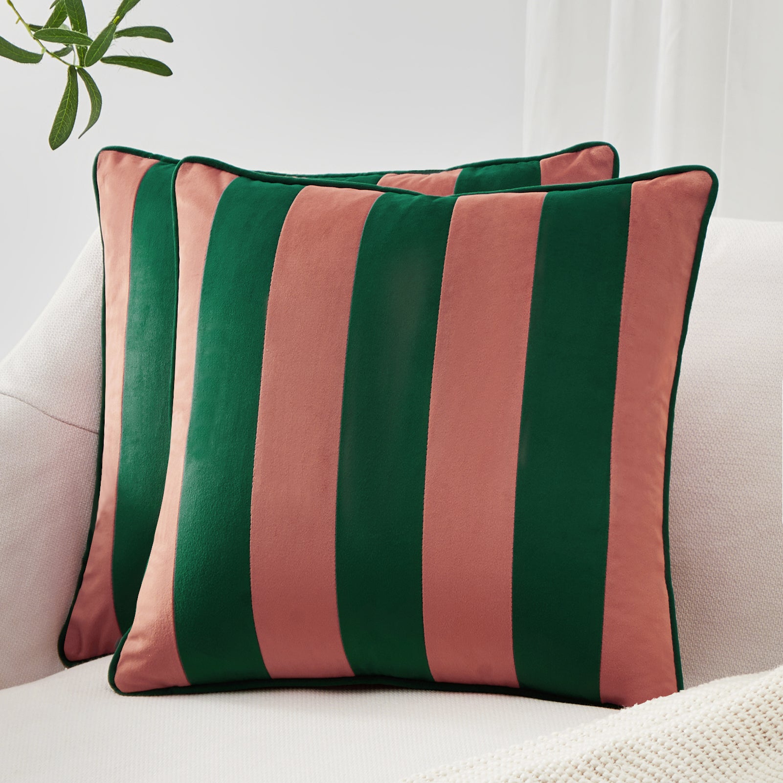 Striped green and pink pillow on a white sofa with a light background
