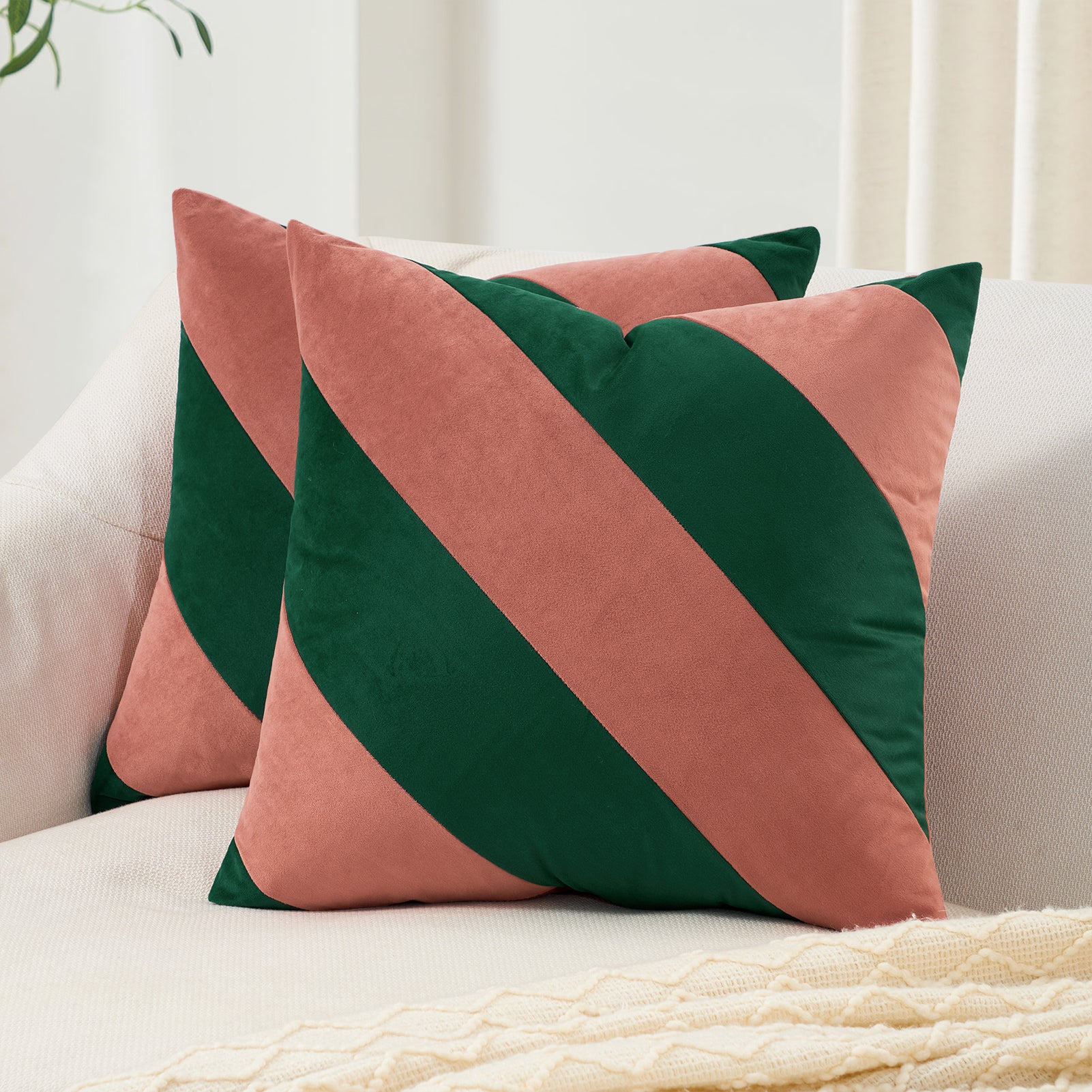 Two decorative pillows with green and pink diagonal stripes on a couch.
