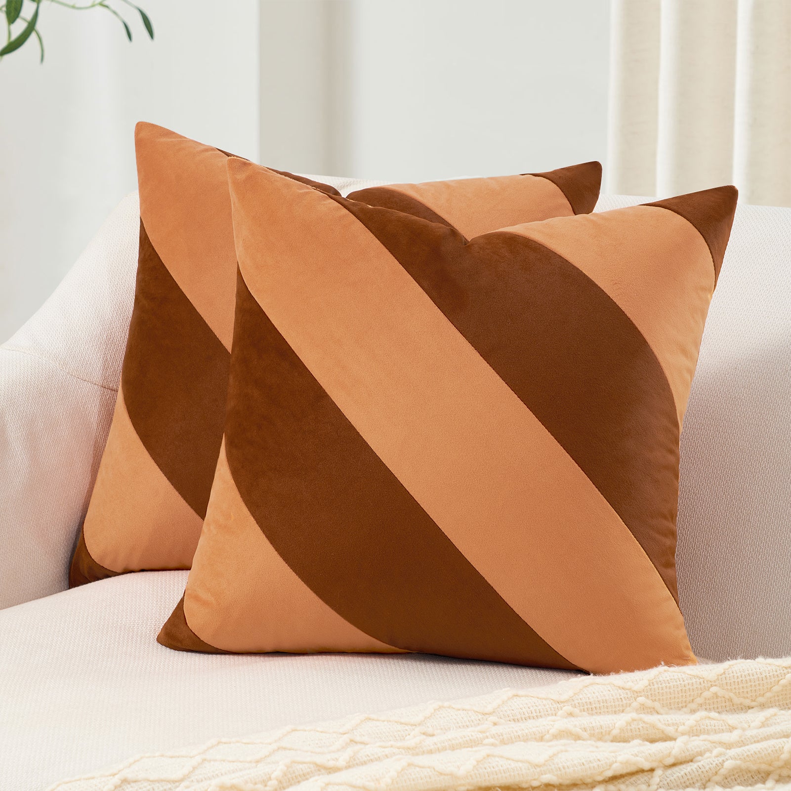 Two brown and orange striped pillows on a white sofa with a neutral background