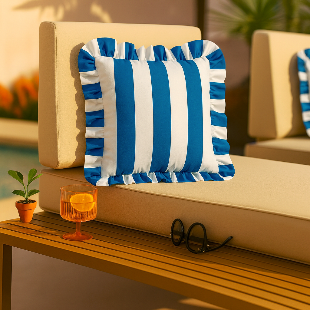 Blue and white striped pillow on a beige outdoor sofa with a small table and plant in the foreground.