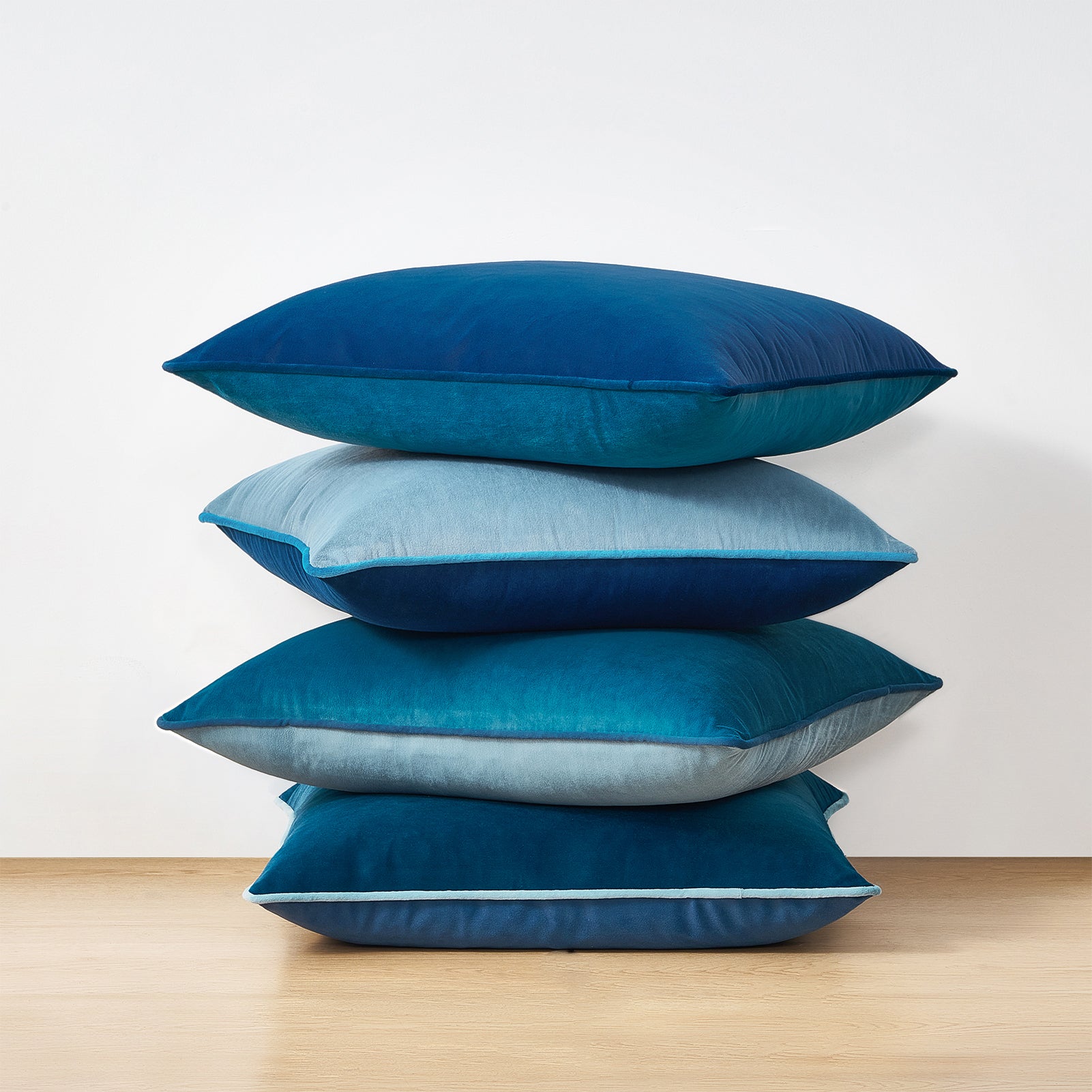 Stack of blue pillows on a wooden surface with a white background
