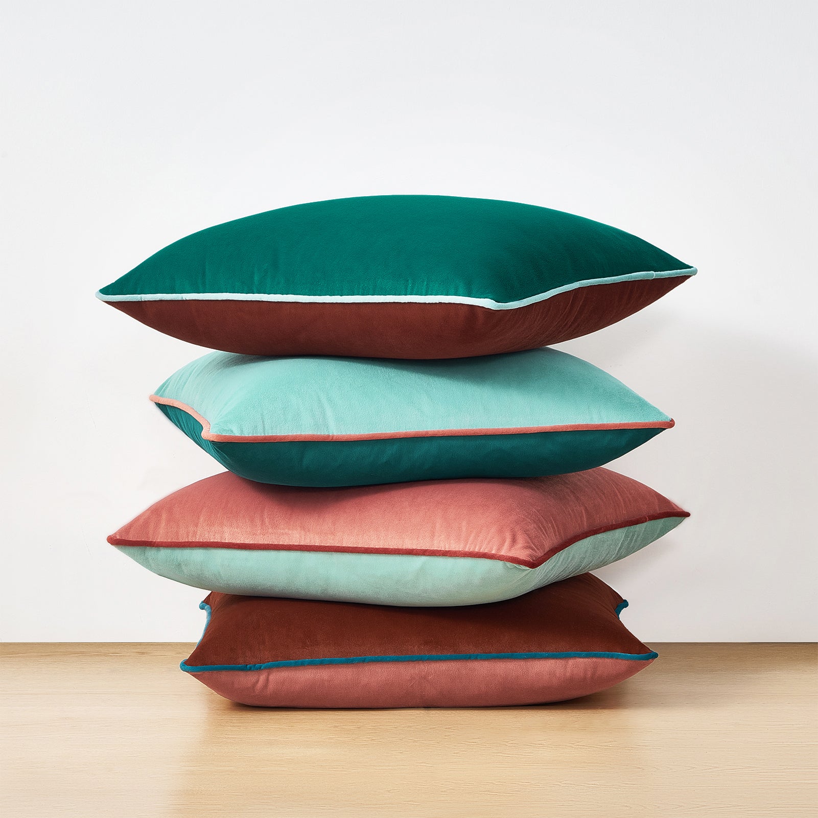 Stack of colorful pillows on a wooden surface with a white background