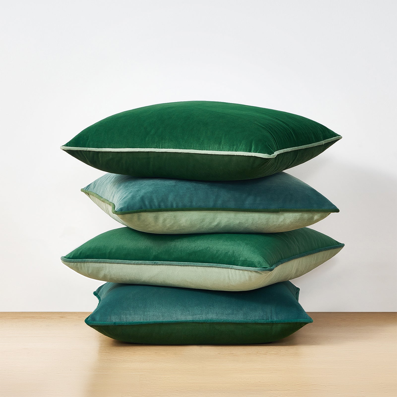 Stack of green pillows on a wooden surface with a white background