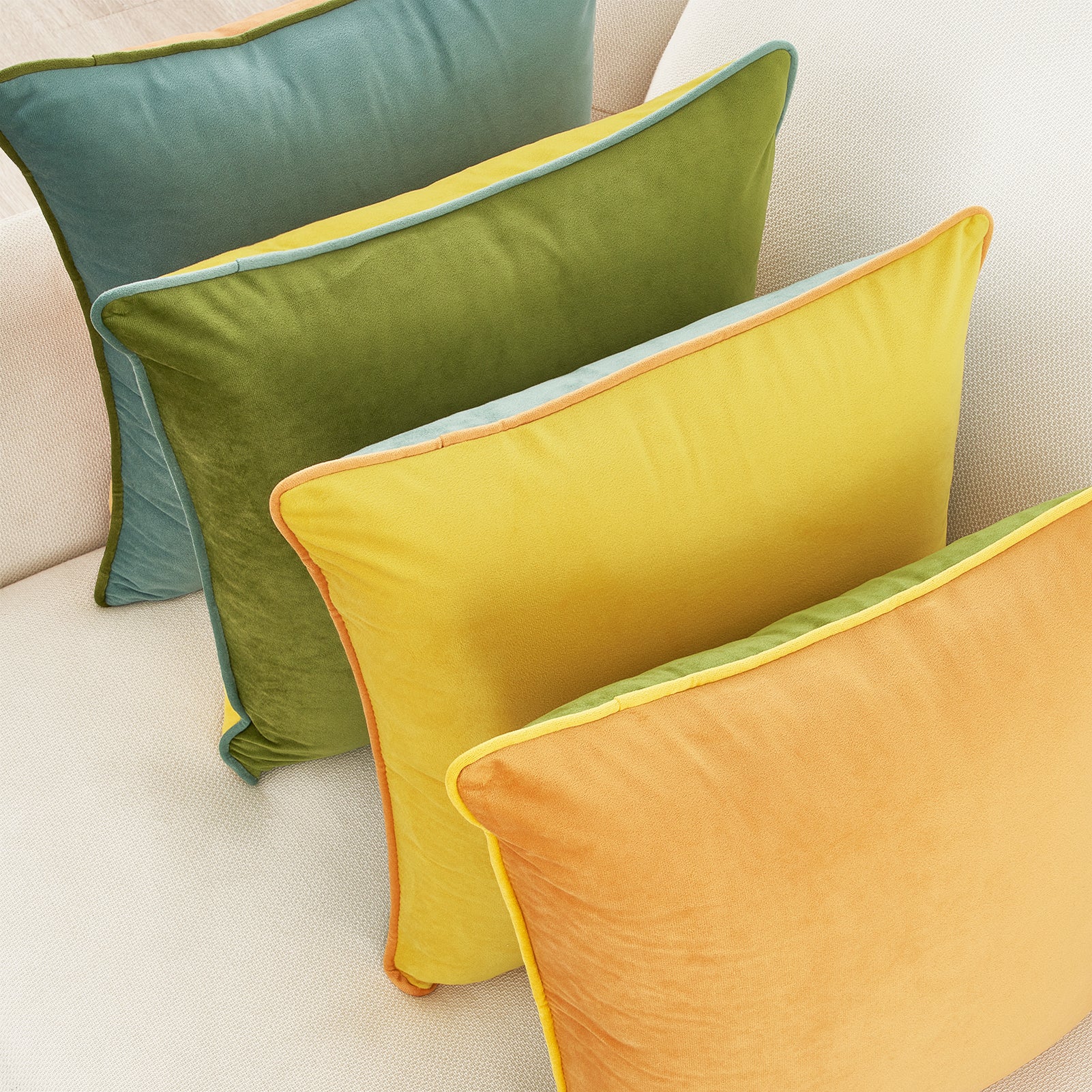 Four colorful pillows on a light-colored sofa.