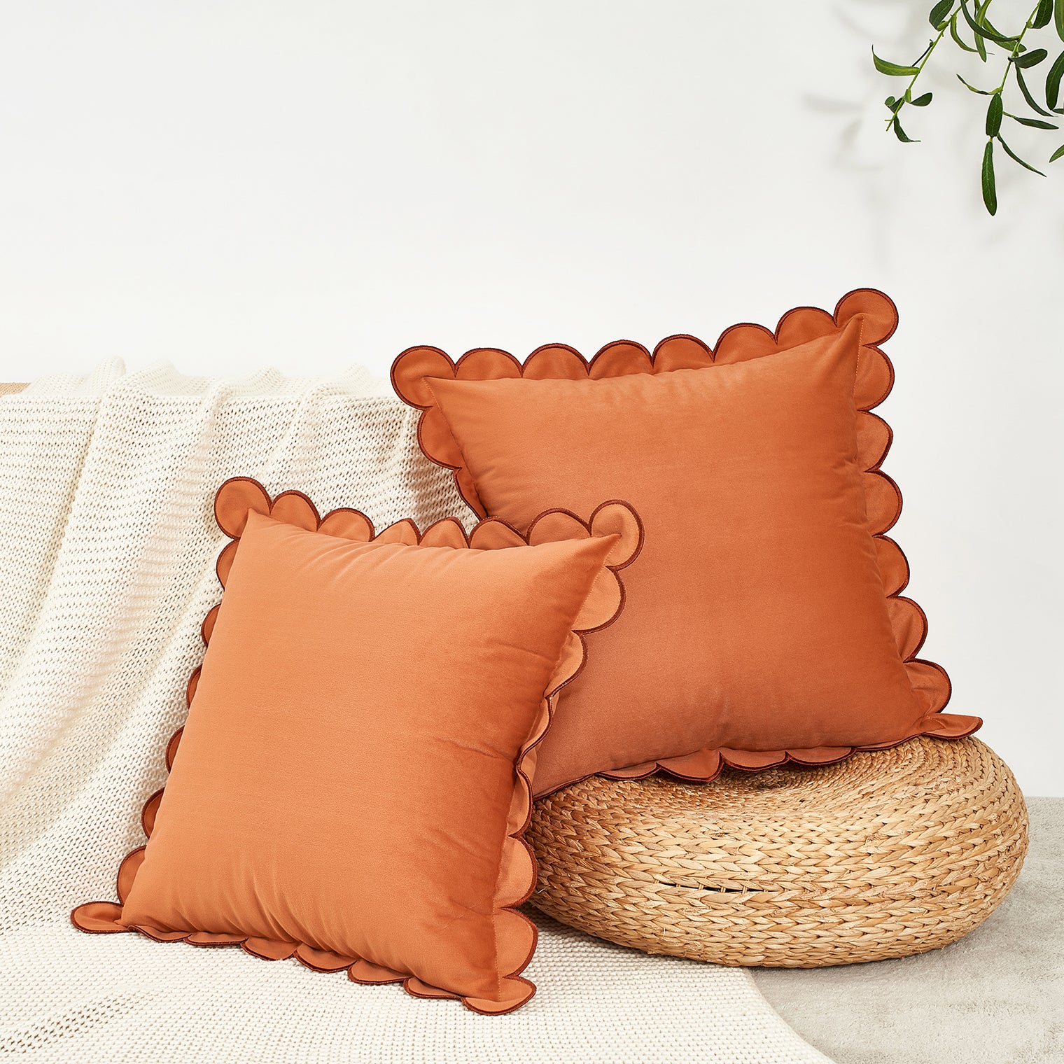 Two orange pillows with scalloped edges on a textured surface.