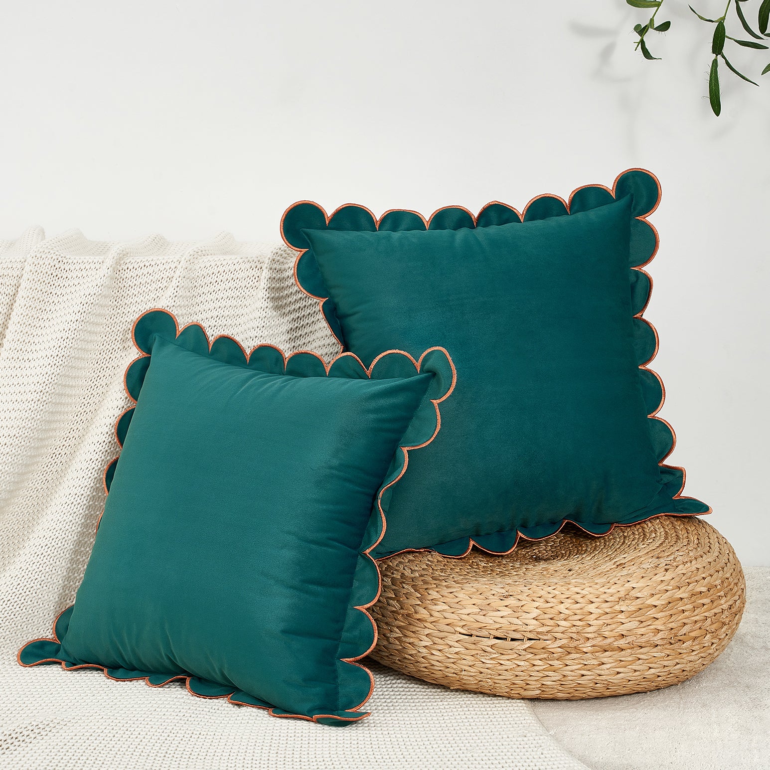 Teal pillows with scalloped edges on a textured surface