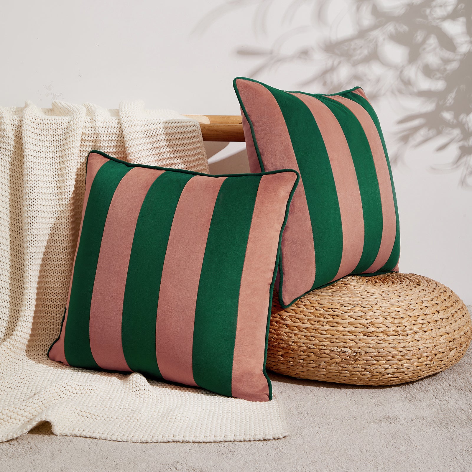 Two striped pillows in green and pink on a textured surface with a woven object.