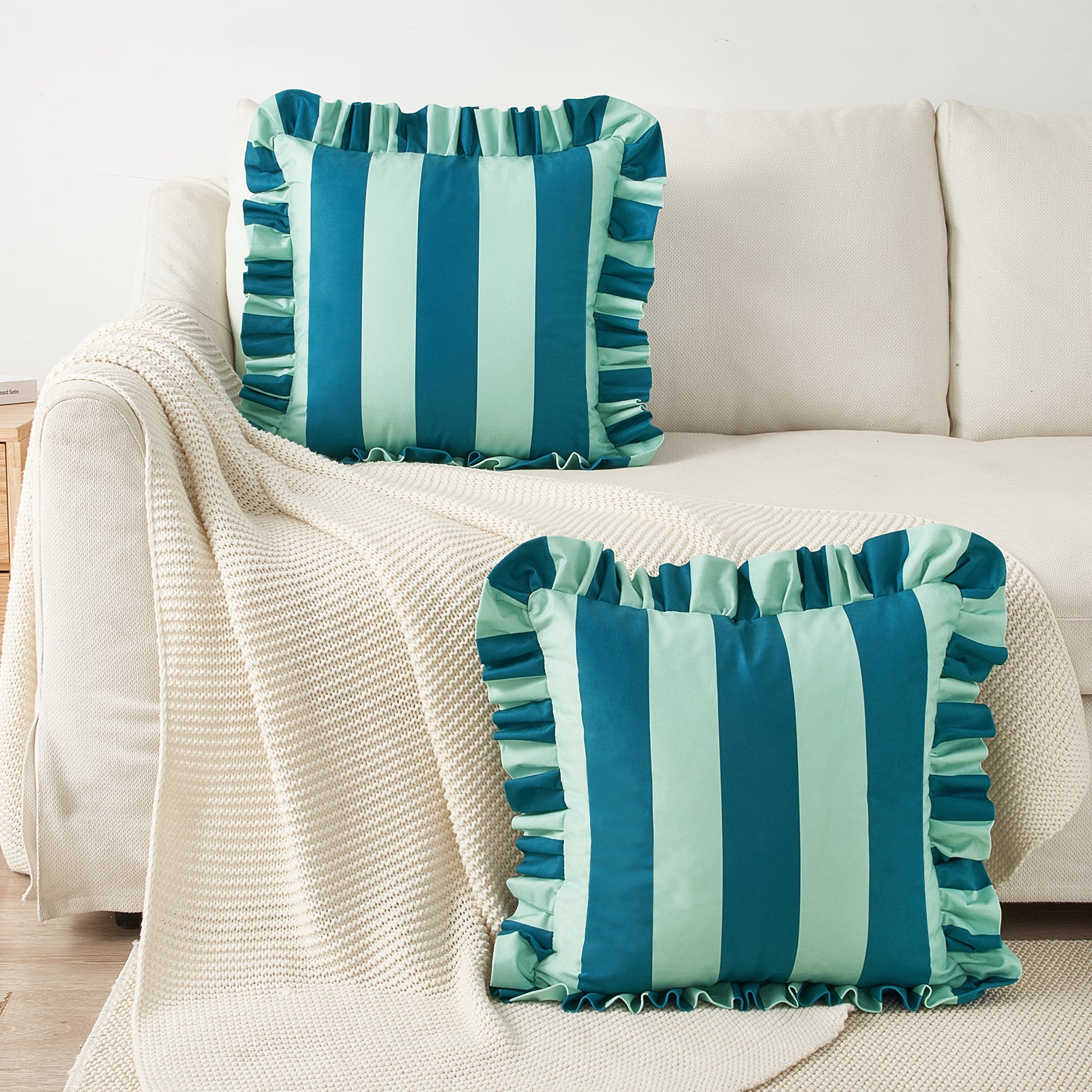 Two striped pillows with ruffled edges on a beige sofa.
