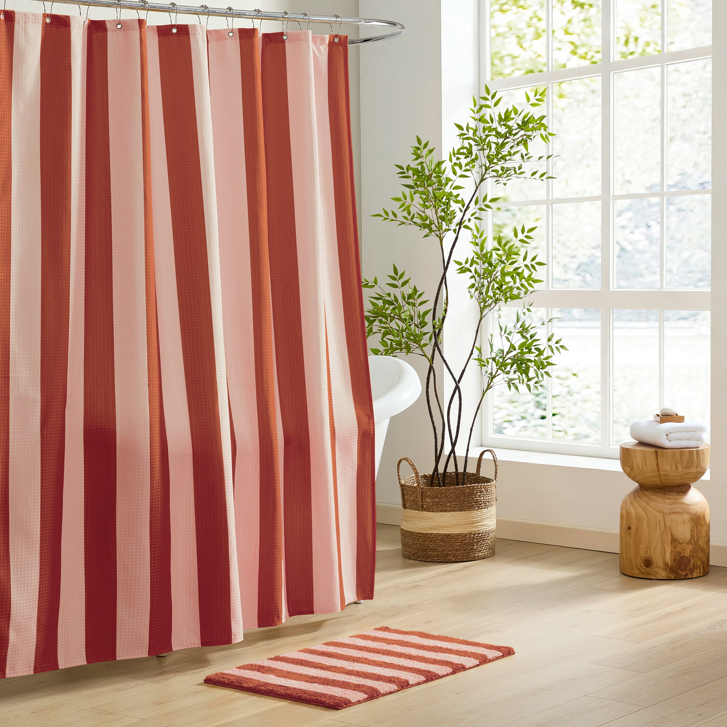 Bathroom with red and pink striped shower curtain and matching rug.