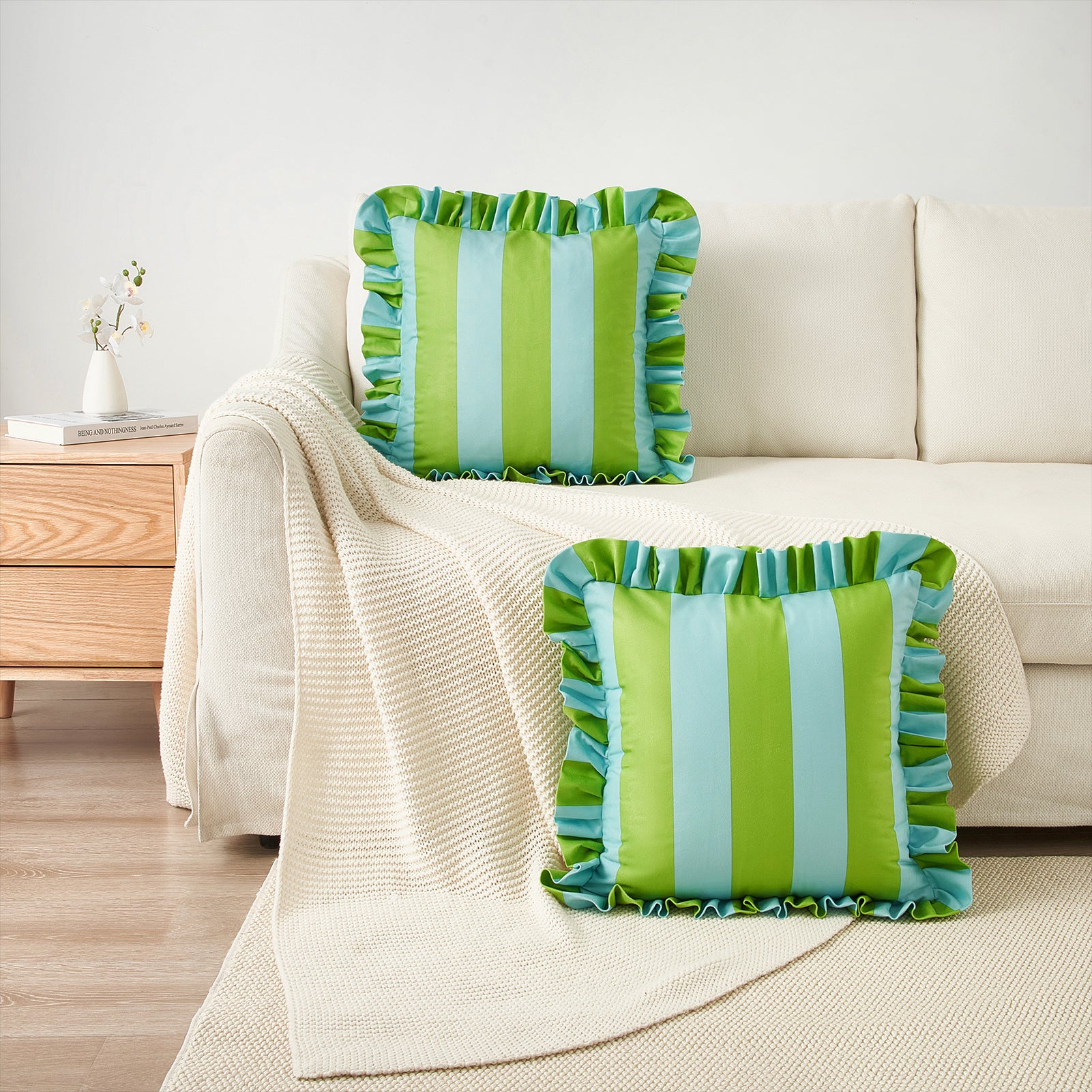 Green and blue striped pillows on a beige sofa in a living room setting.