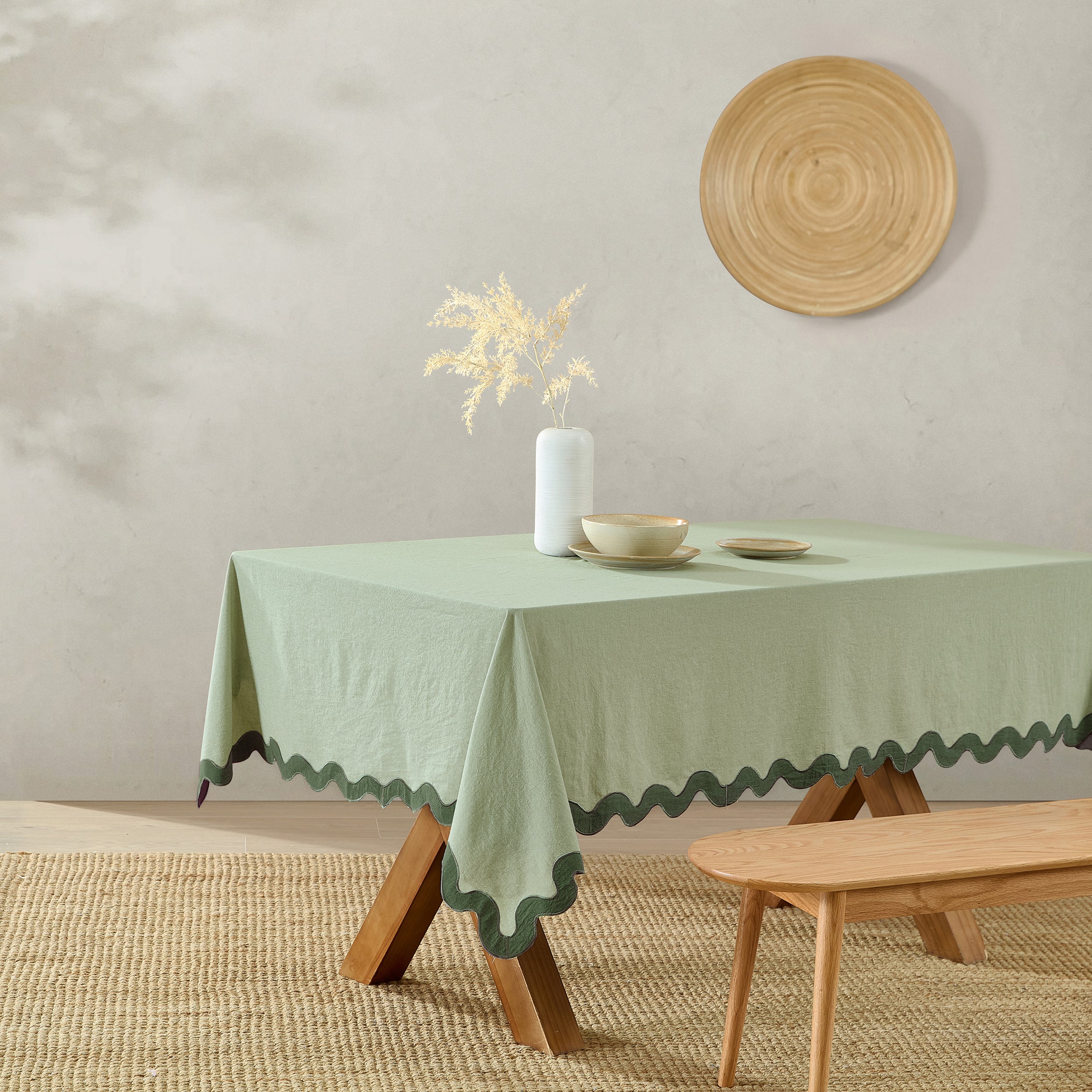 Green tablecloth on a wooden table with decorative items against a plain wall.