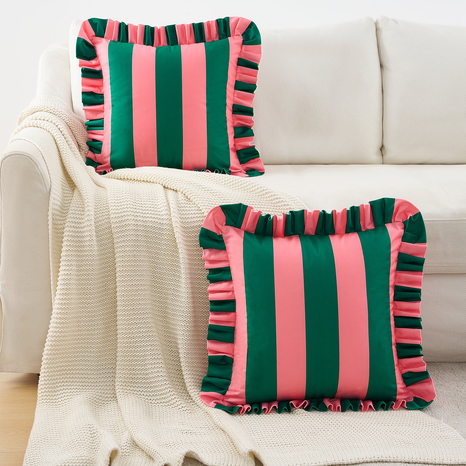Two green and pink striped pillows with ruffles on a beige sofa.