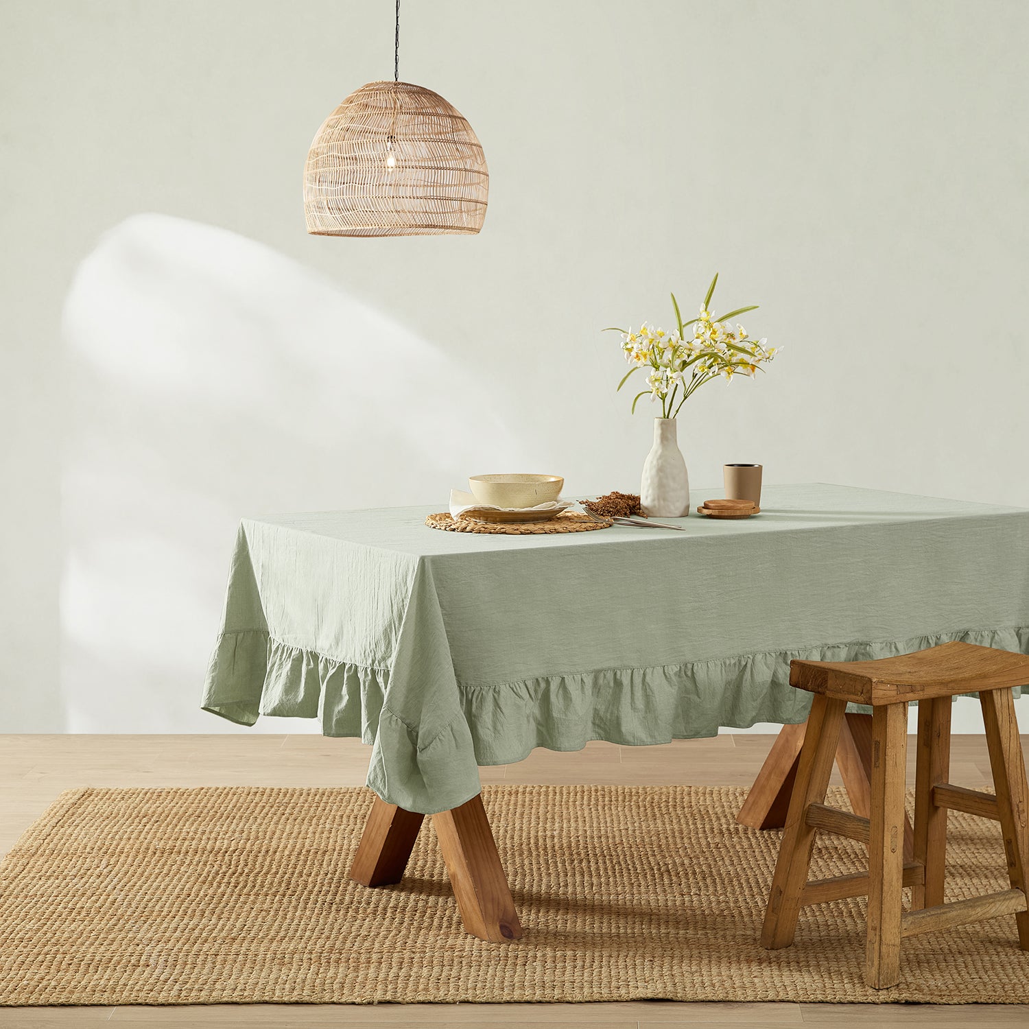 Dining room with a green tablecloth on a table, wooden stool, and pendant light.