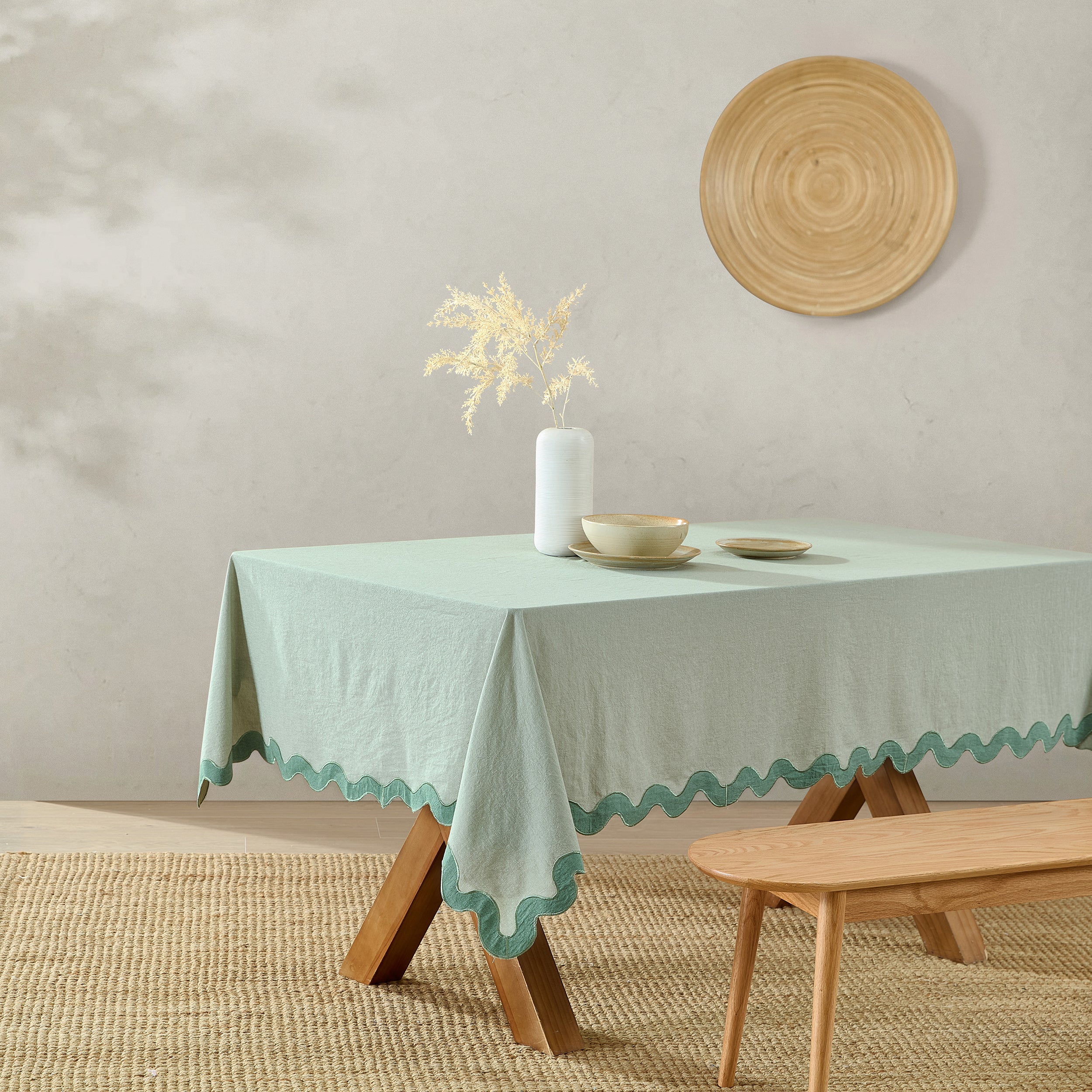 Light green tablecloth on a wooden table with decorative items against a plain wall.