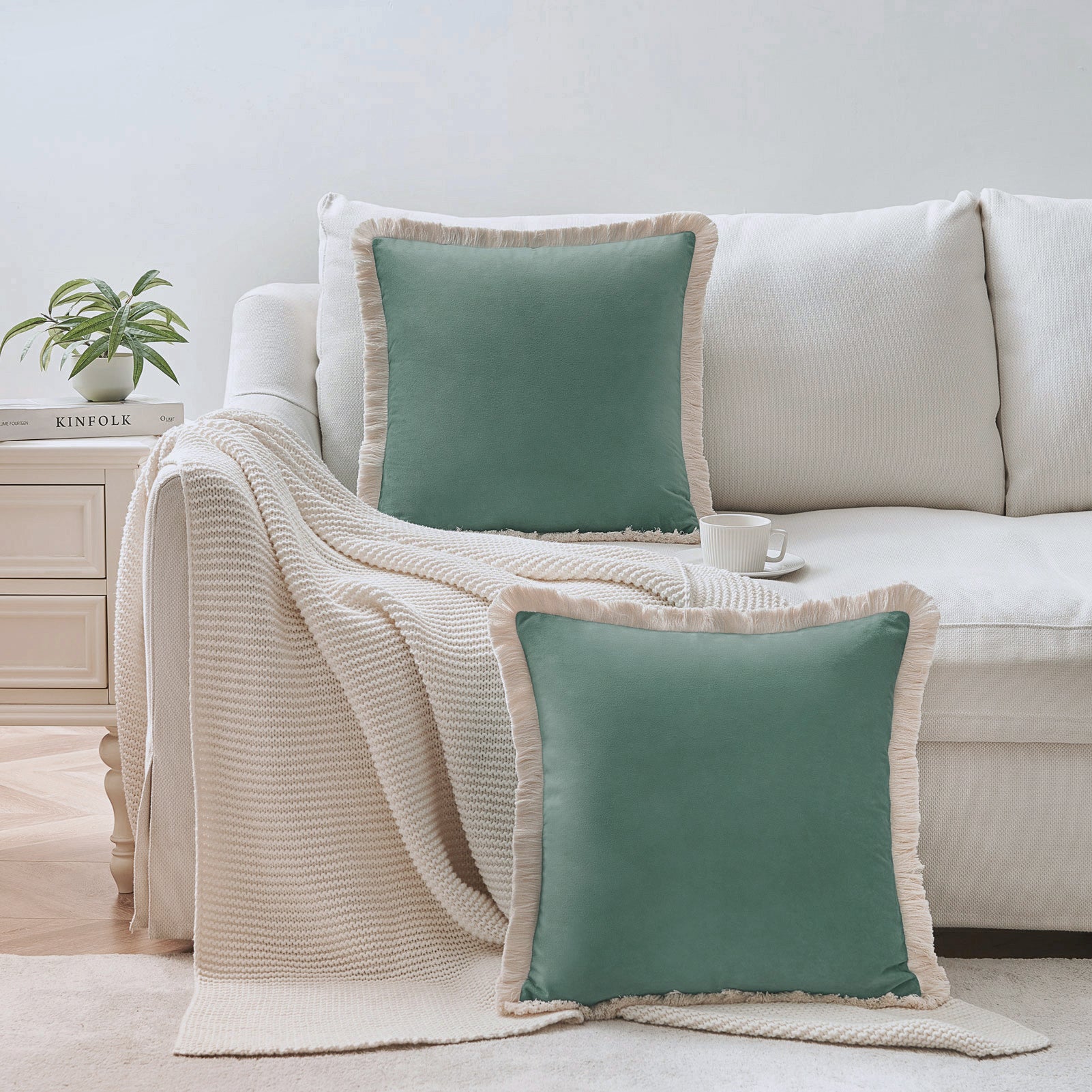 Teal pillows with beige trim on a white sofa in a living room setting.