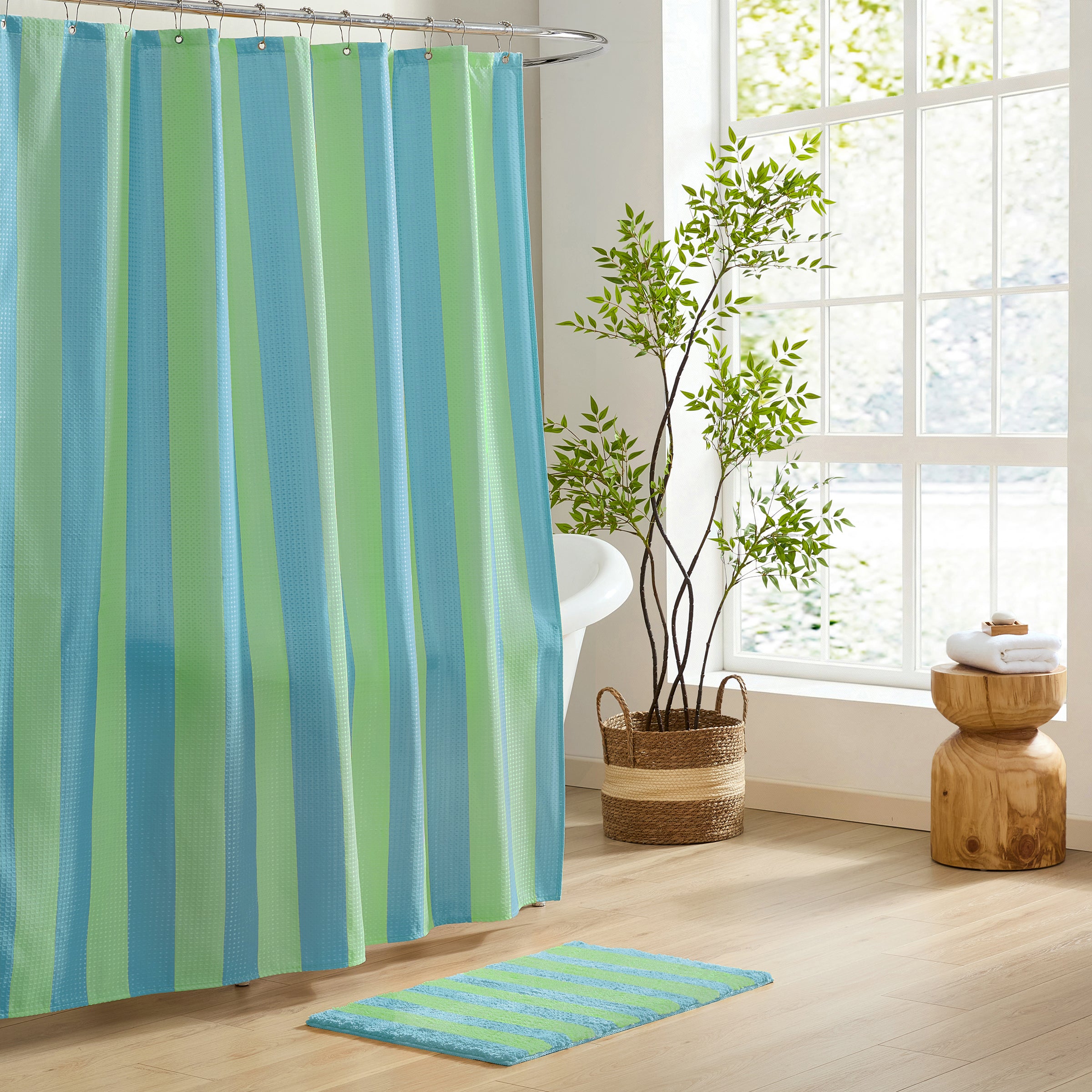 Bathroom with a striped shower curtain and matching rug, featuring a plant and wooden stool.