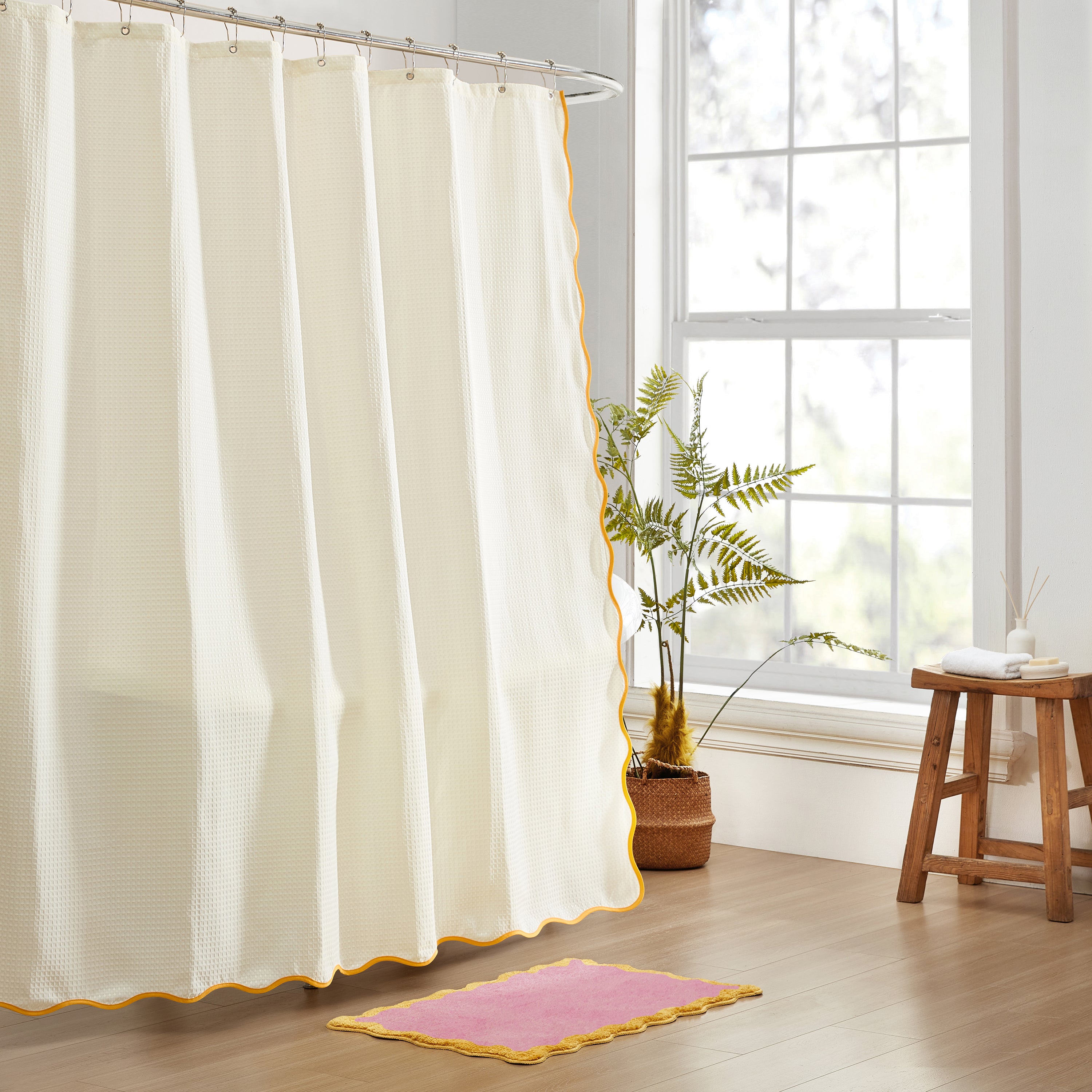 White shower curtain with yellow trim in a bathroom setting.