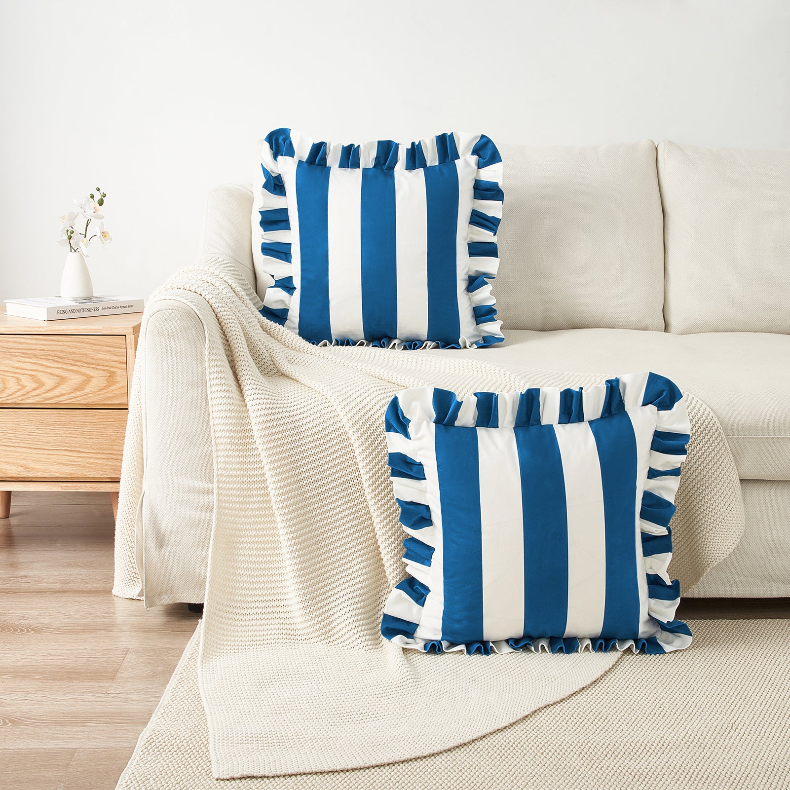 Blue and white striped pillows on a beige sofa with a wooden side table.