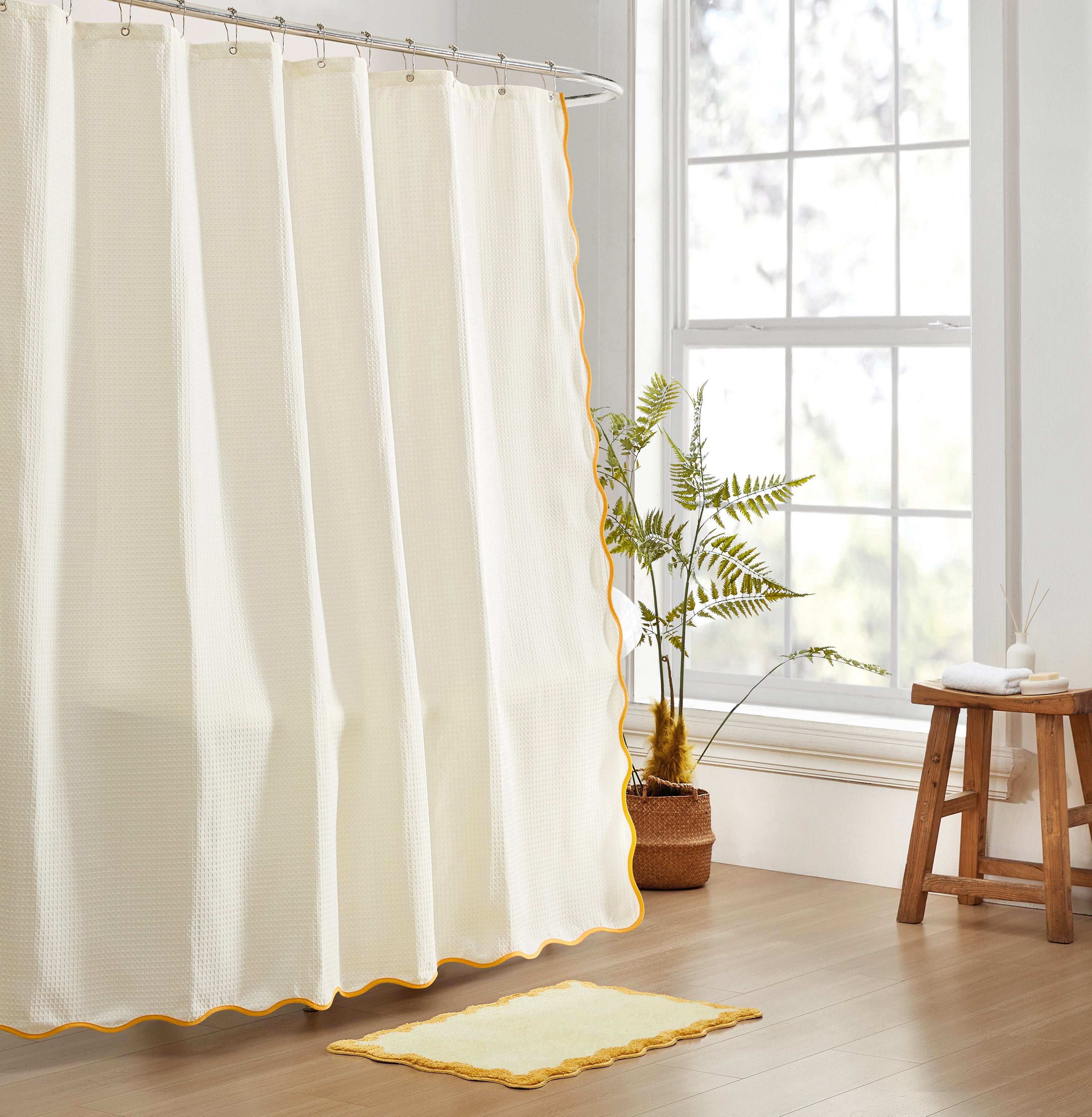 White shower curtain with yellow trim in a bathroom setting.