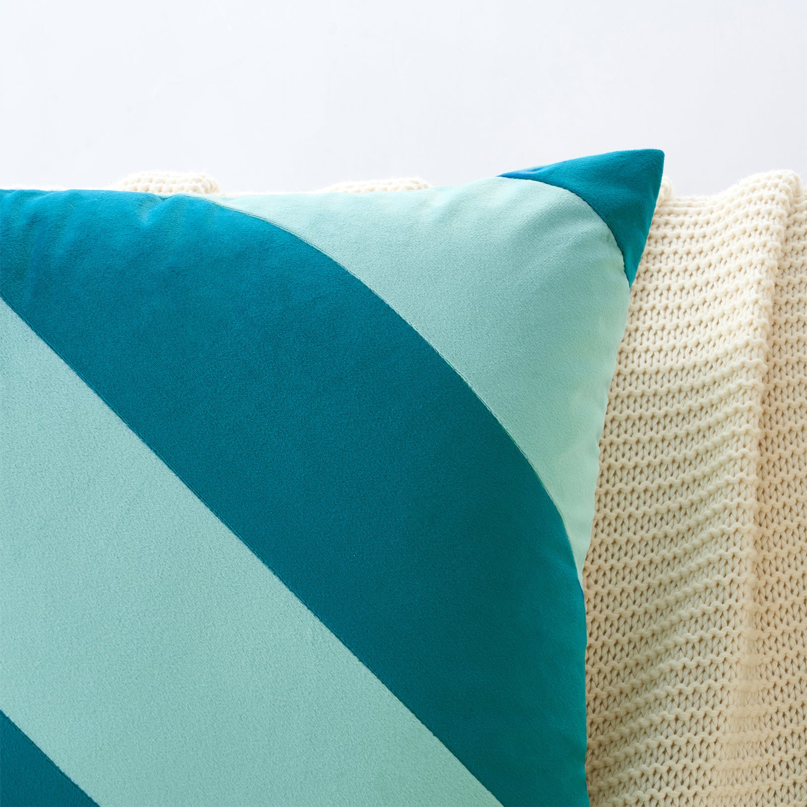 Teal and light blue pillow on a textured beige surface
