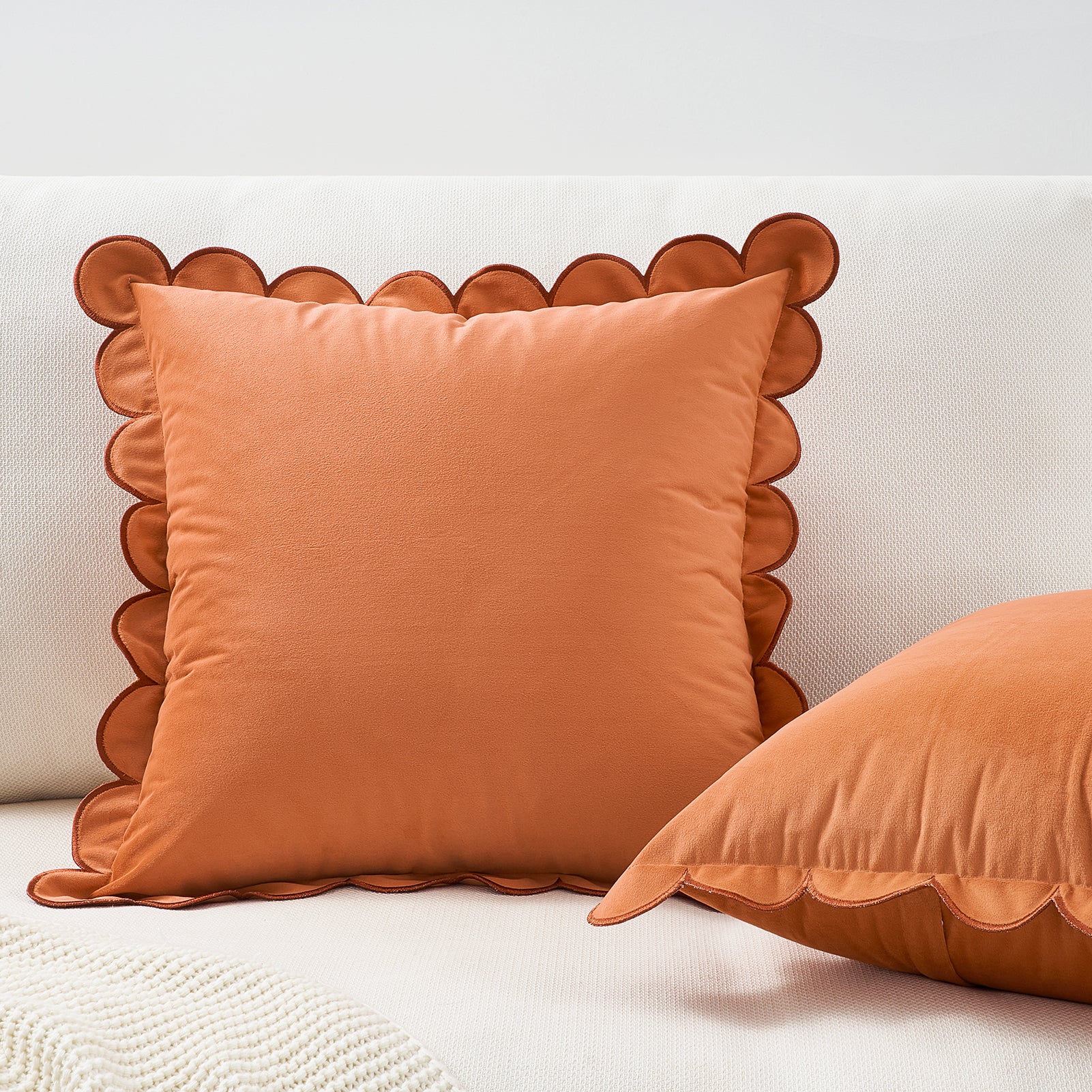Orange pillow with scalloped edge on a white background