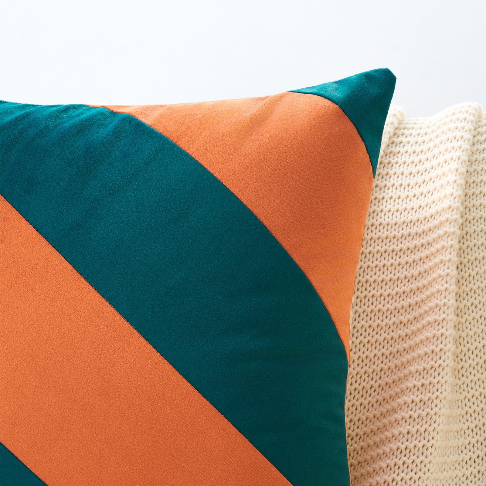 Colorful pillow with orange and teal stripes on a beige surface