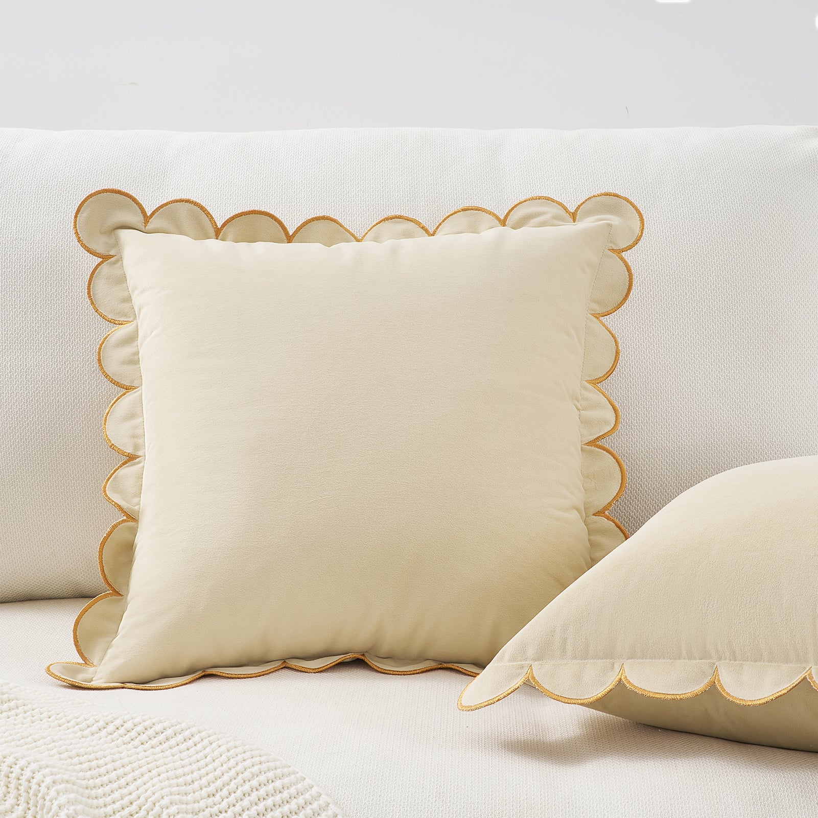 Beige pillow with scalloped edge on a white sofa