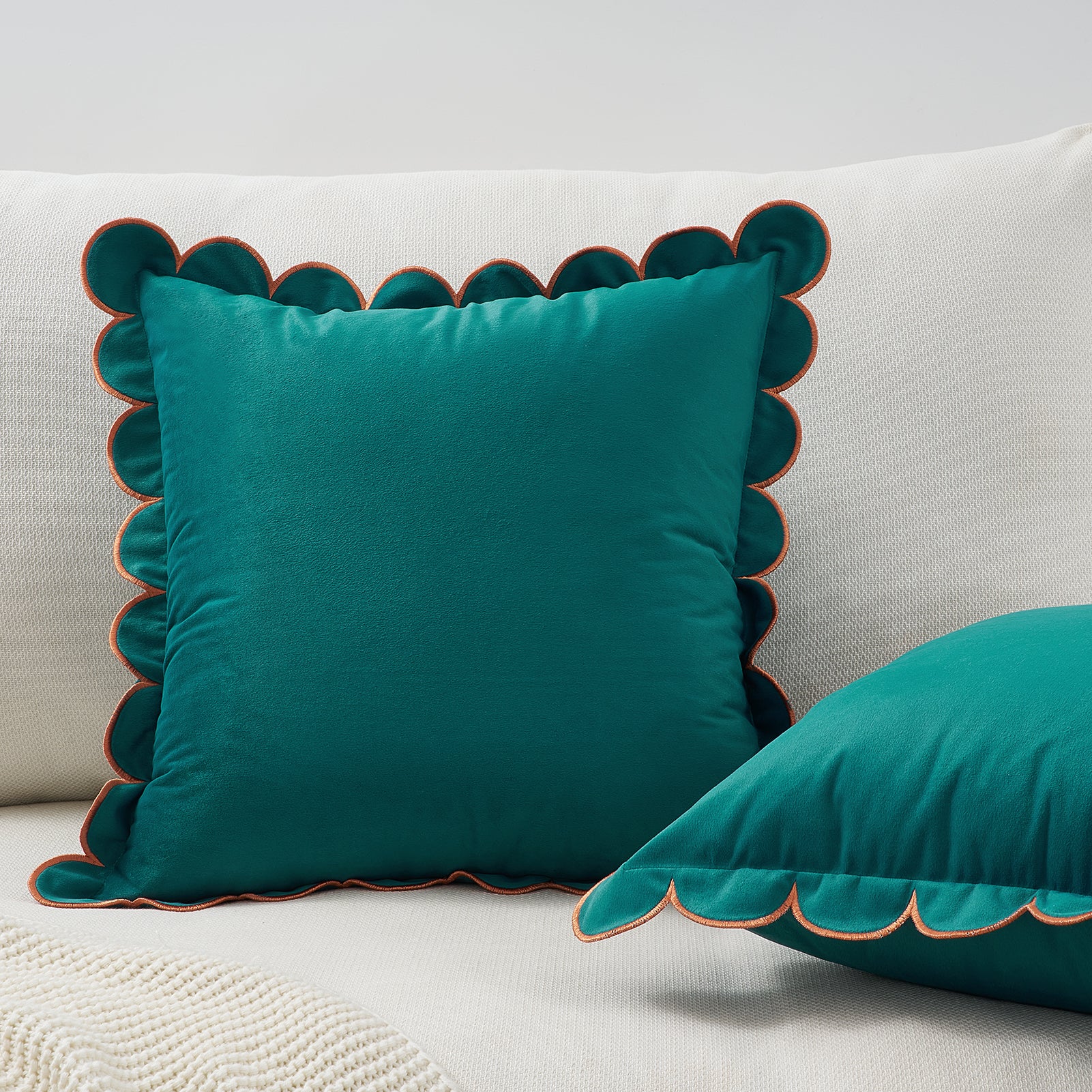 Teal pillows with scalloped edges on a white sofa