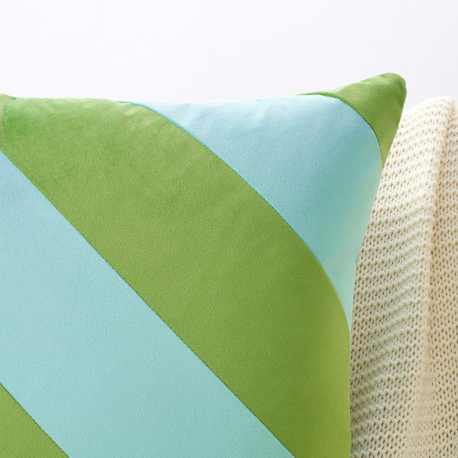Green and light blue pillow on a beige surface