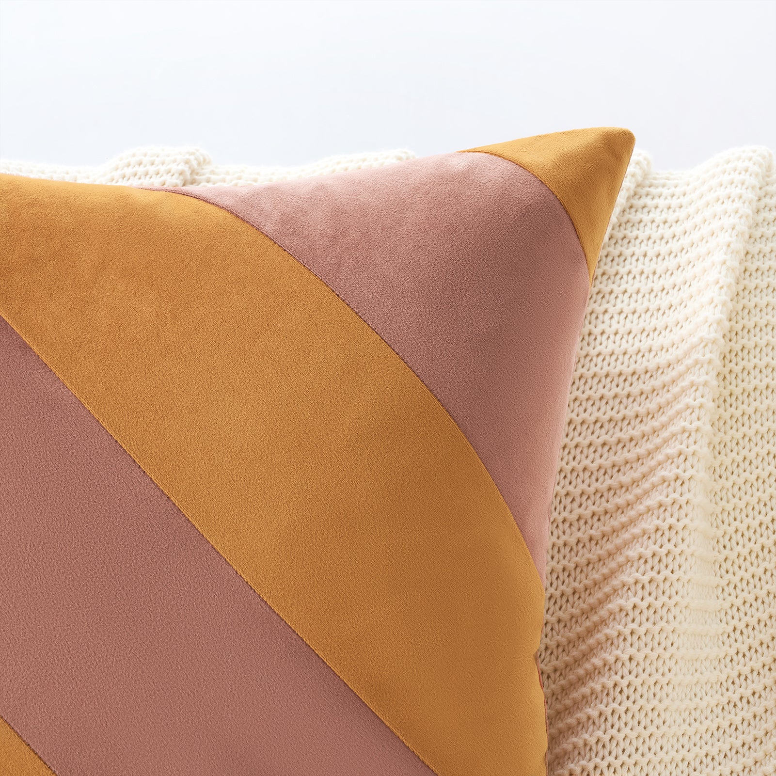 Color-blocked pillow with mustard yellow and pink on a textured surface