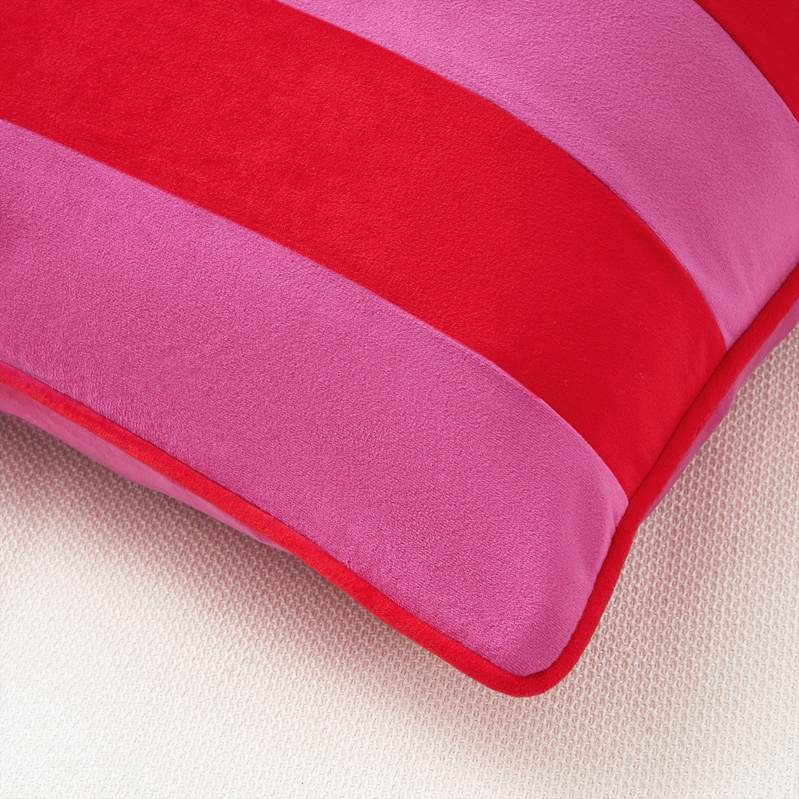 Close-up of a pink and red striped pillow on a beige surface