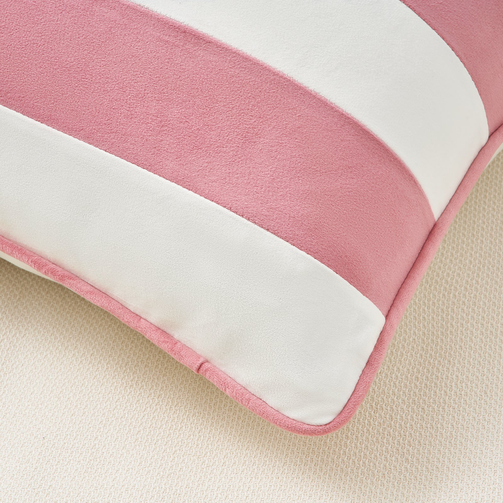 Close-up of a pink and white cushion on a beige surface