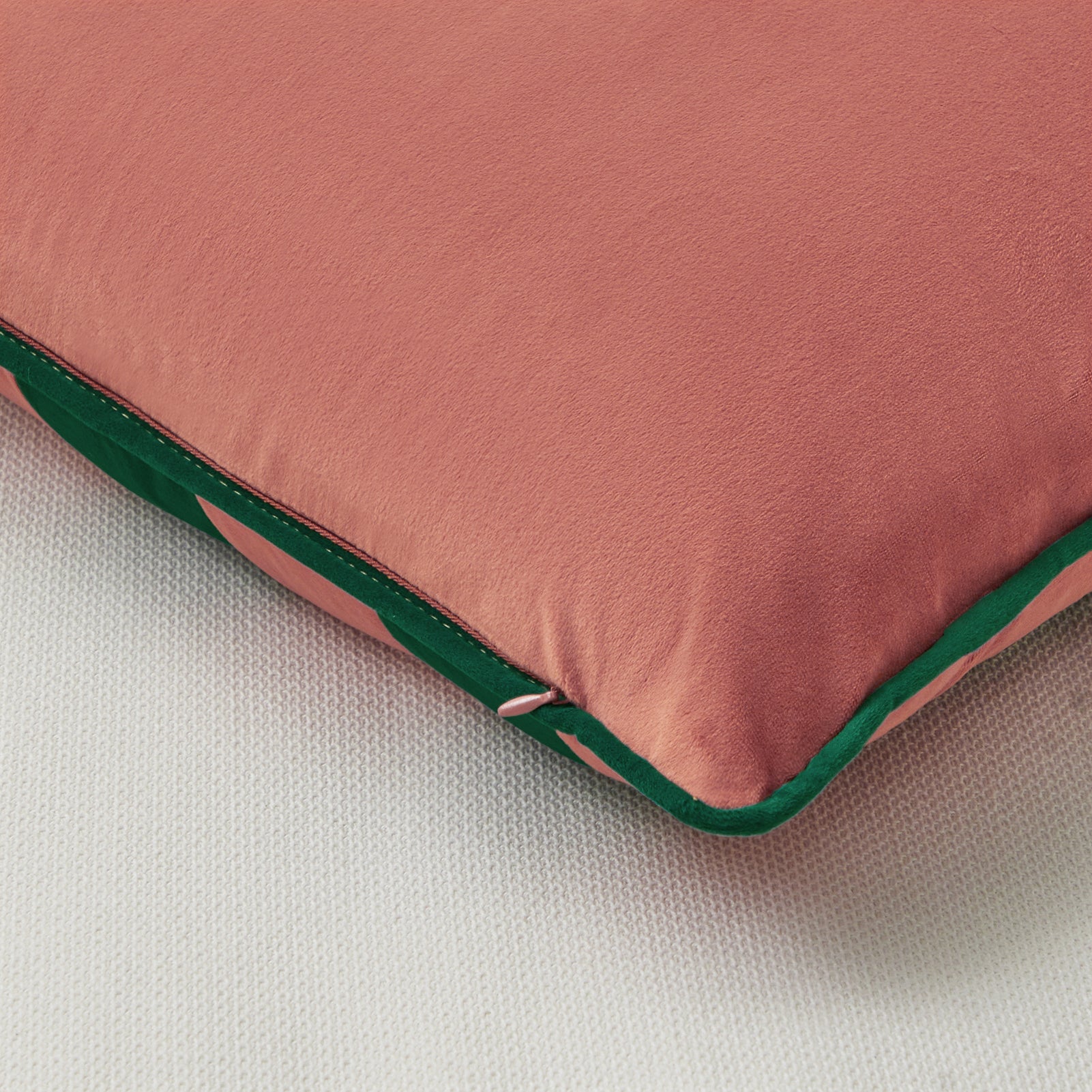 Pink cushion with green trim on a white background