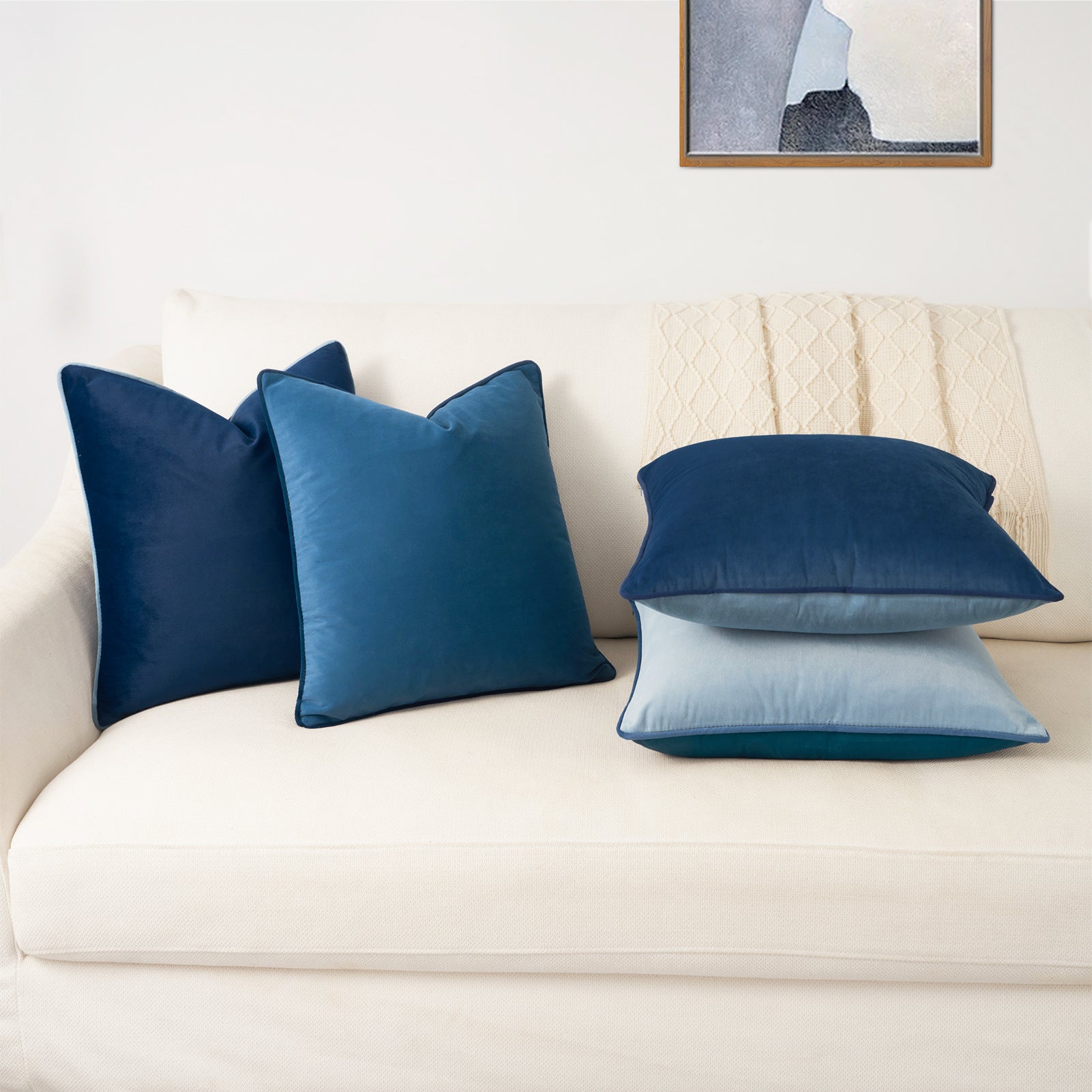 Blue pillows on a white sofa with a neutral wall and framed picture in the background