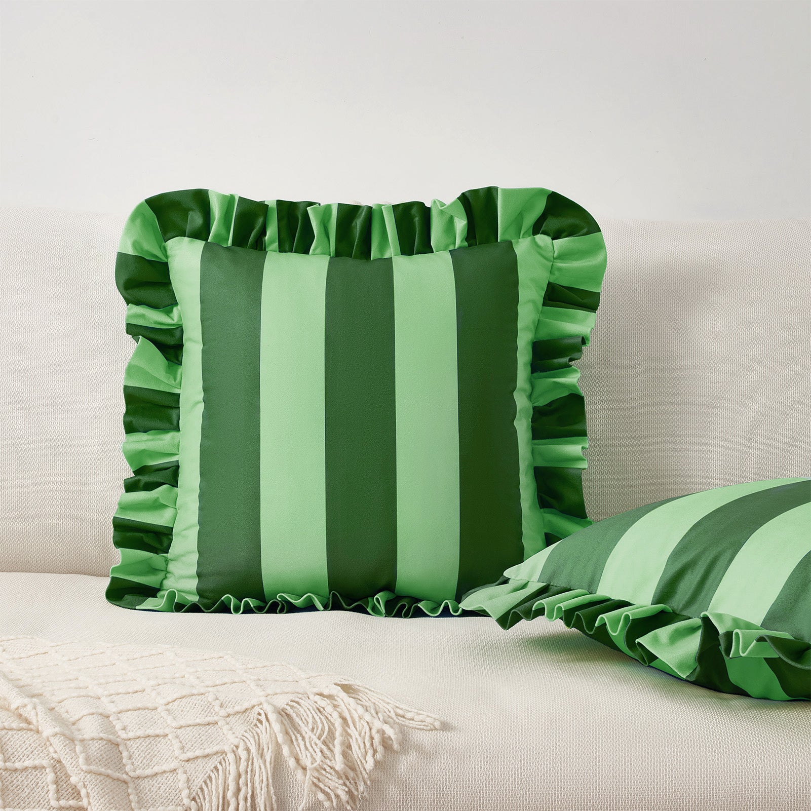 Green striped pillows with ruffled edges on a neutral background