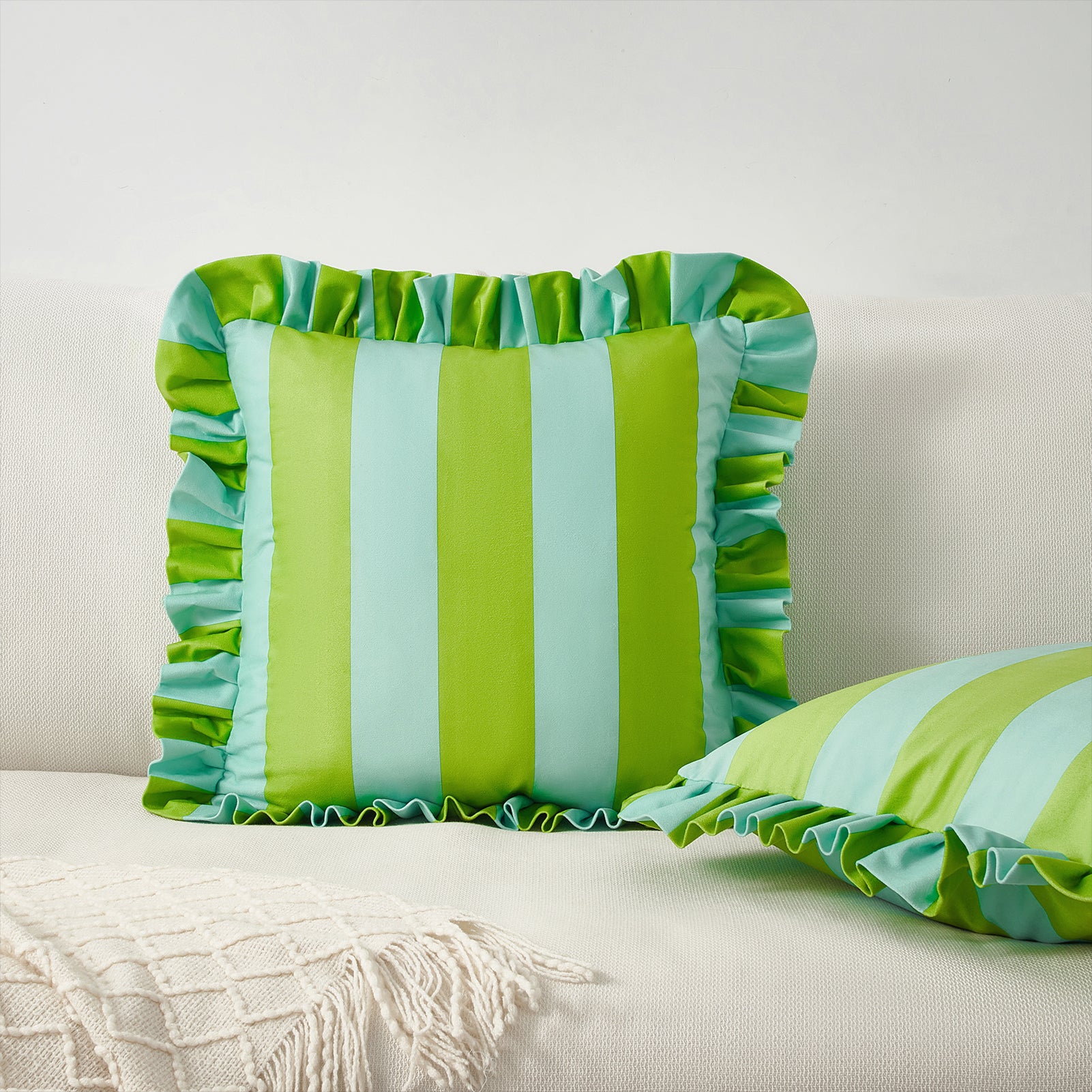 Two green and blue striped pillows with ruffled edges on a white surface.