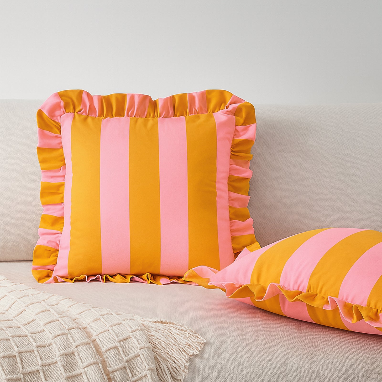 Two striped pillows with ruffled edges on a neutral background