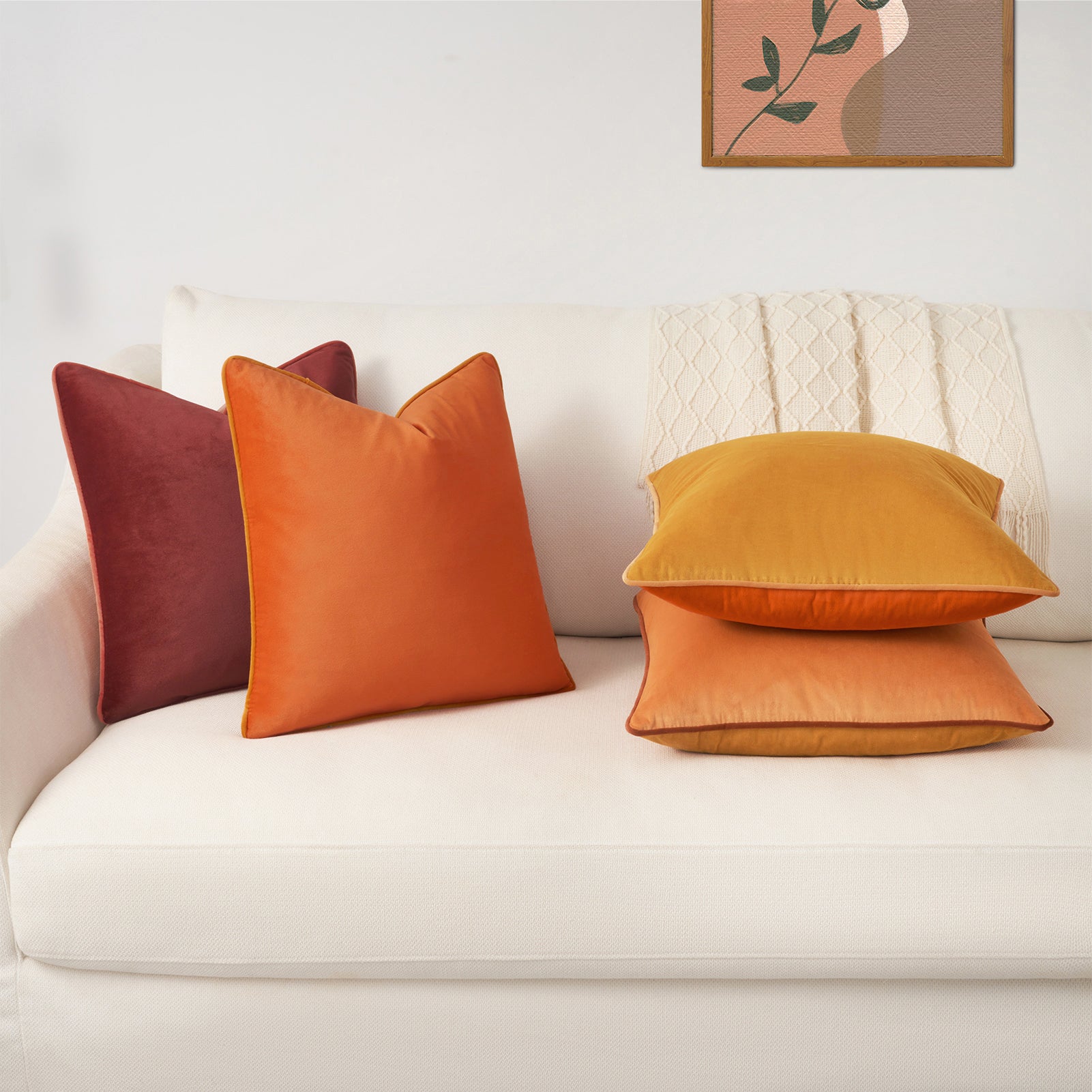 Colorful pillows on a white sofa with a framed abstract painting in the background.