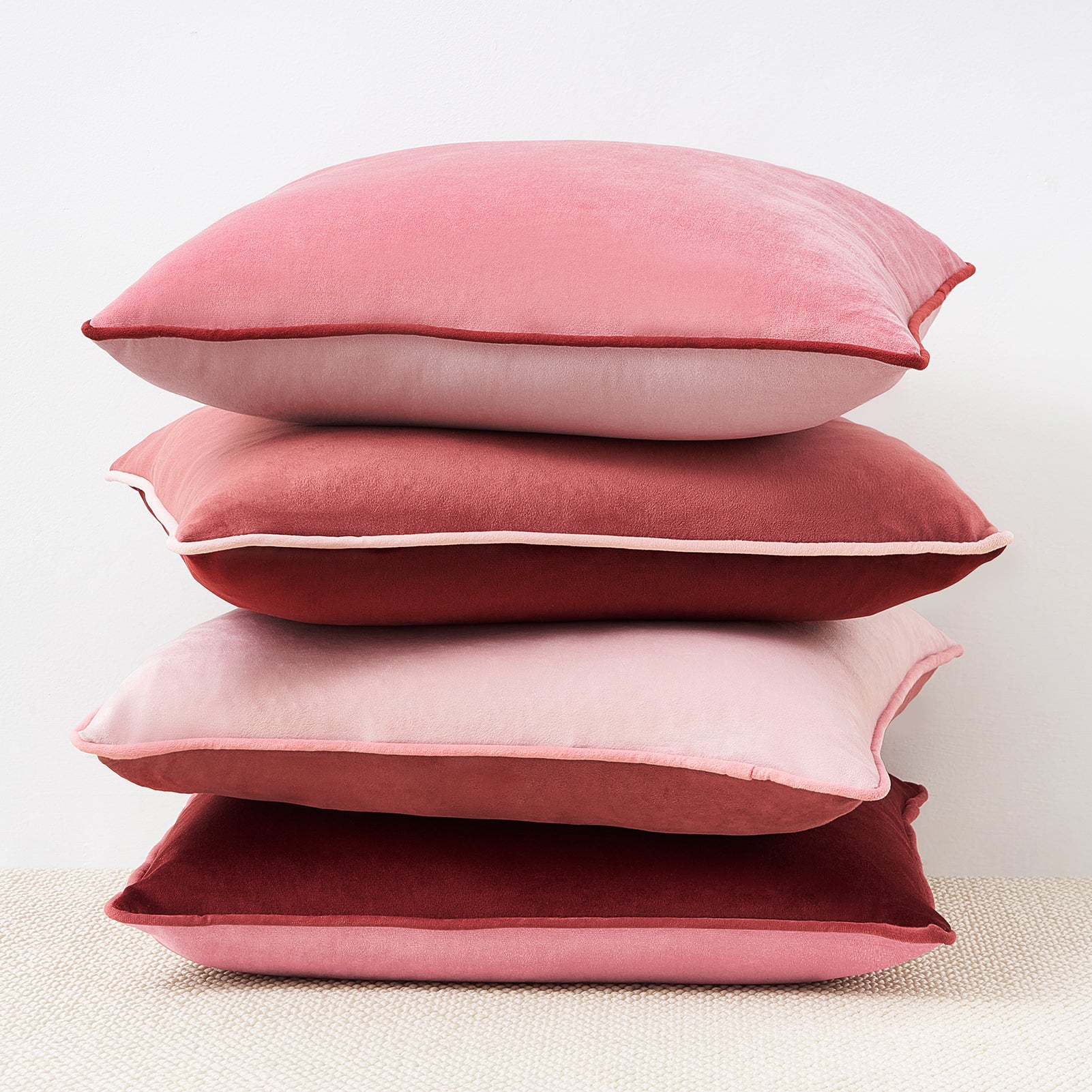 Stack of pink pillows on a textured surface with a light background
