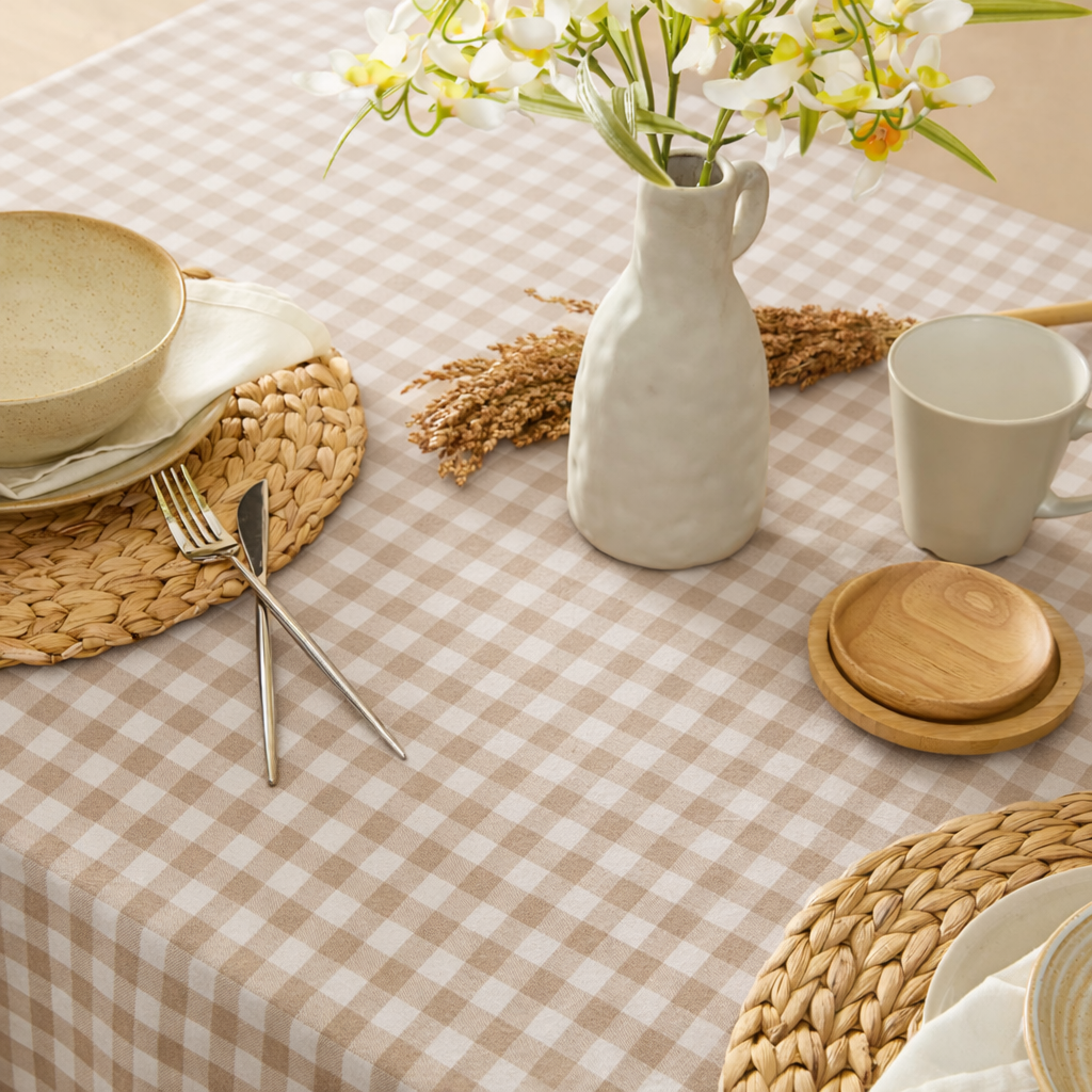 Table setting with checkered tablecloth, ceramic items, and a vase with flowers.