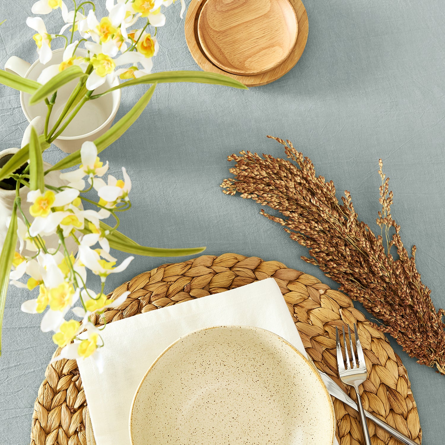Dining table setting with plates, flowers, and a napkin on a gray surface
