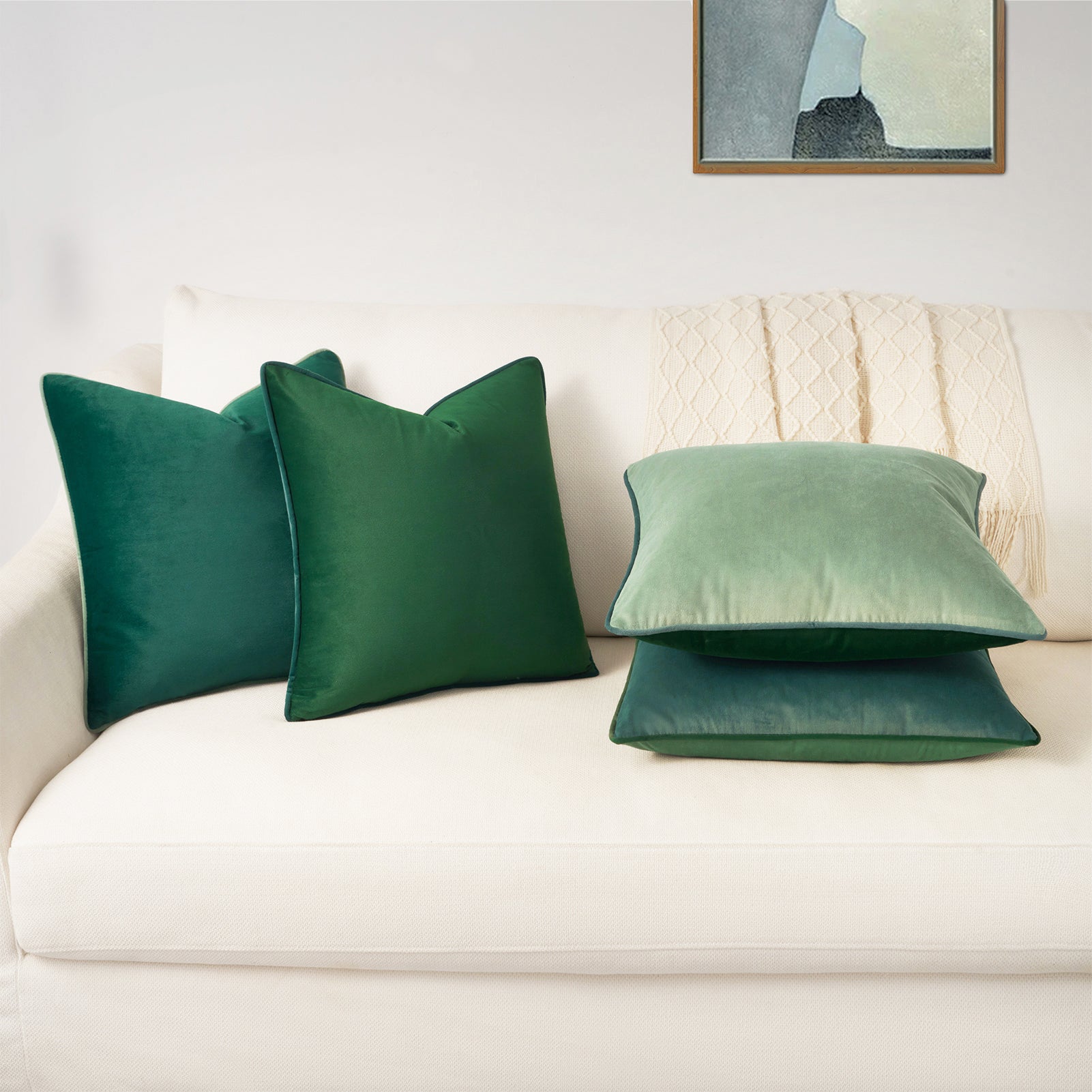 Green pillows on a white sofa with a neutral wall and framed picture in the background