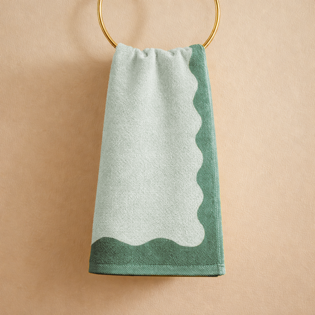 Green and white towel hanging on a gold ring against a beige background